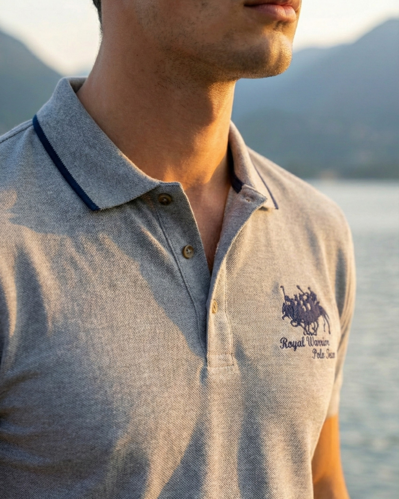 Close-up of light gray embroidered polo shirt collar and logo detail