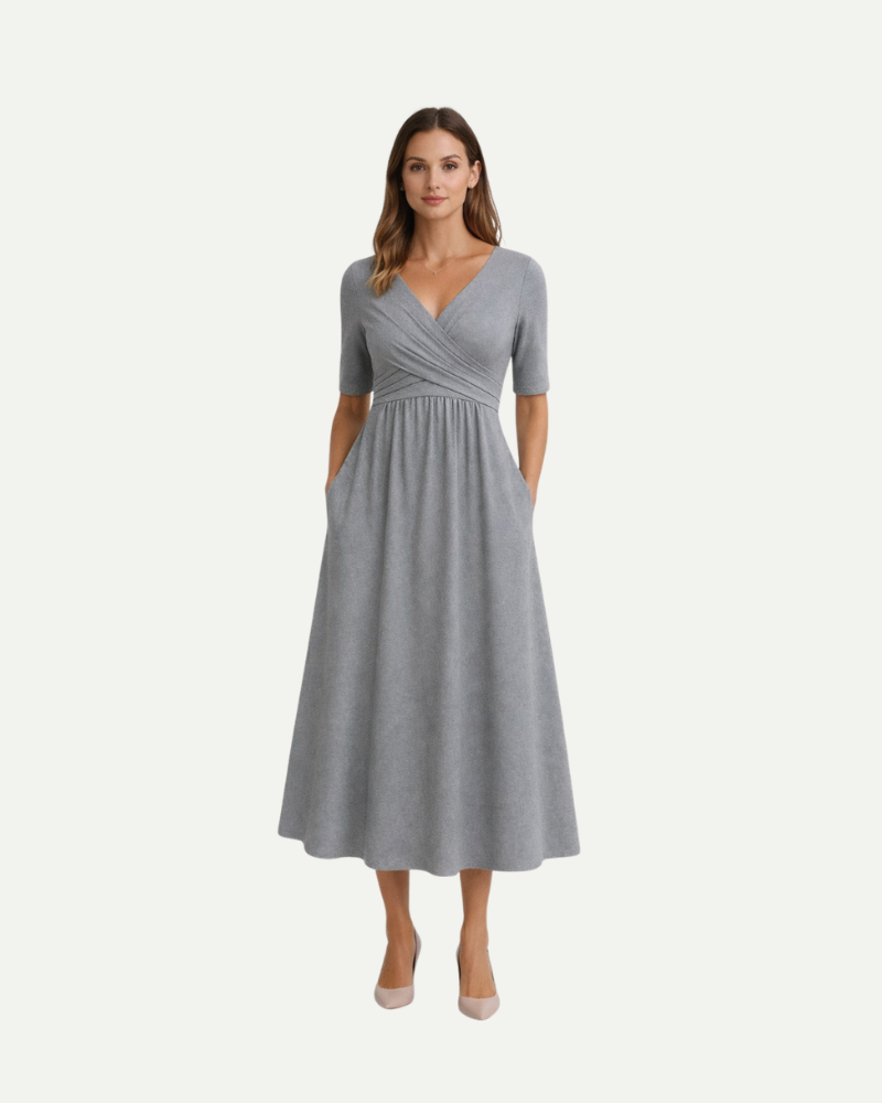 Female model wearing gray V-neck midi dress with empire waist and flowing skirt