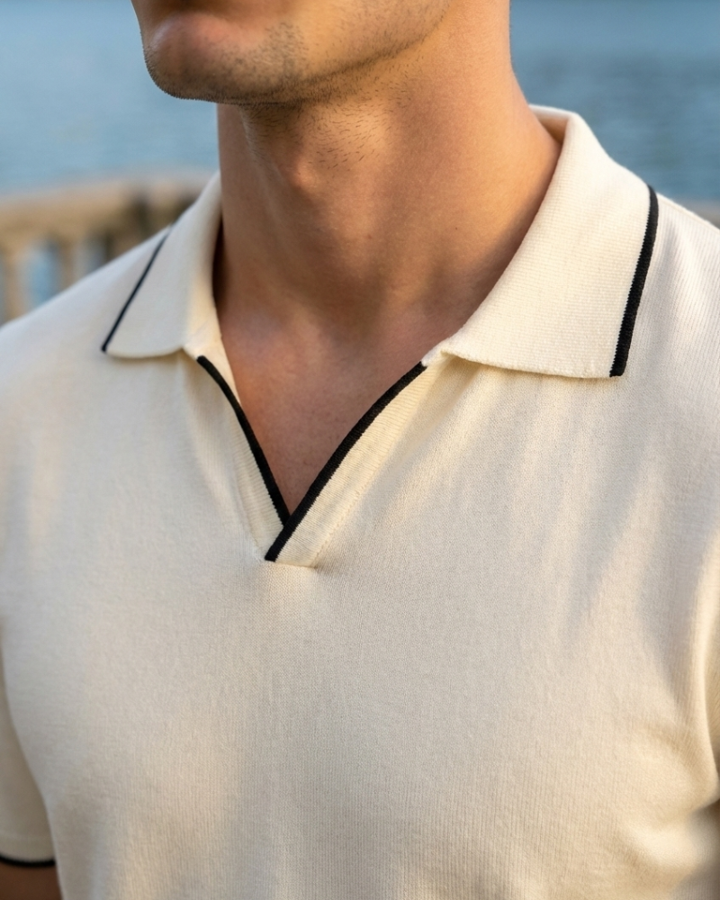 Close-up of beige knit polo shirt open collar with black contrast trim detail