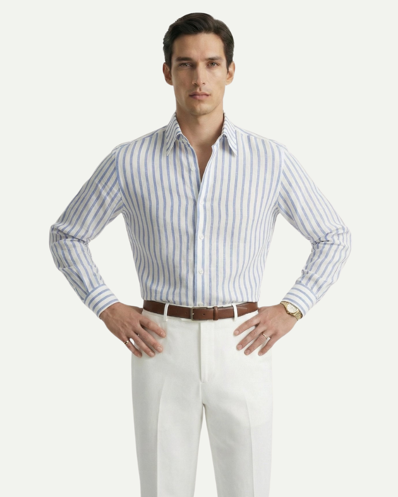 Male model wearing a blue striped linen button-up shirt styled with white trousers