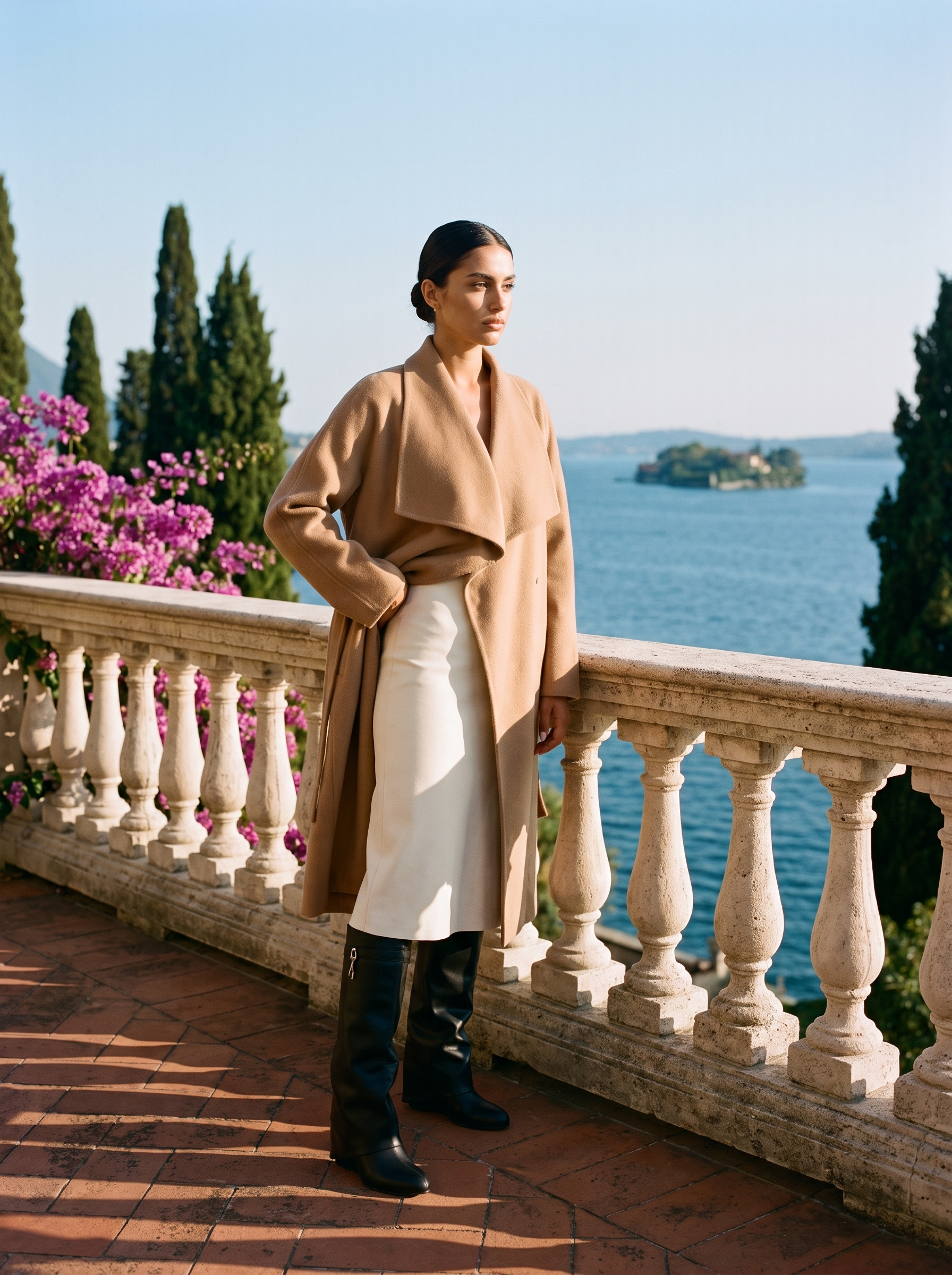 Full body front view of a woman in black fold-over knee high boots and a cream skirt on a Lake Como terrace — Aveloire
