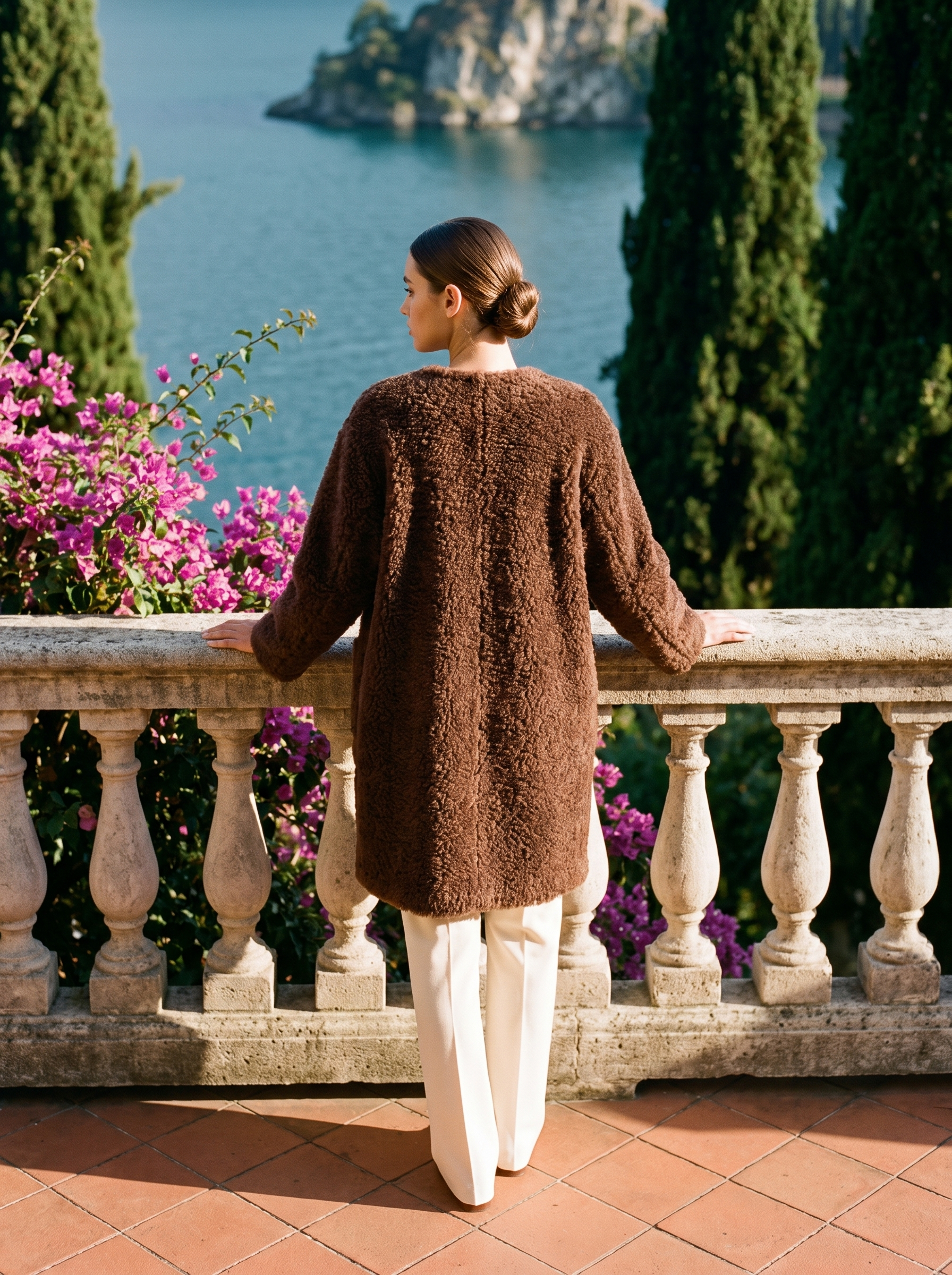 Back view of a coffee-brown shearling teddy coat on a Lake Como terrace — Aveloire