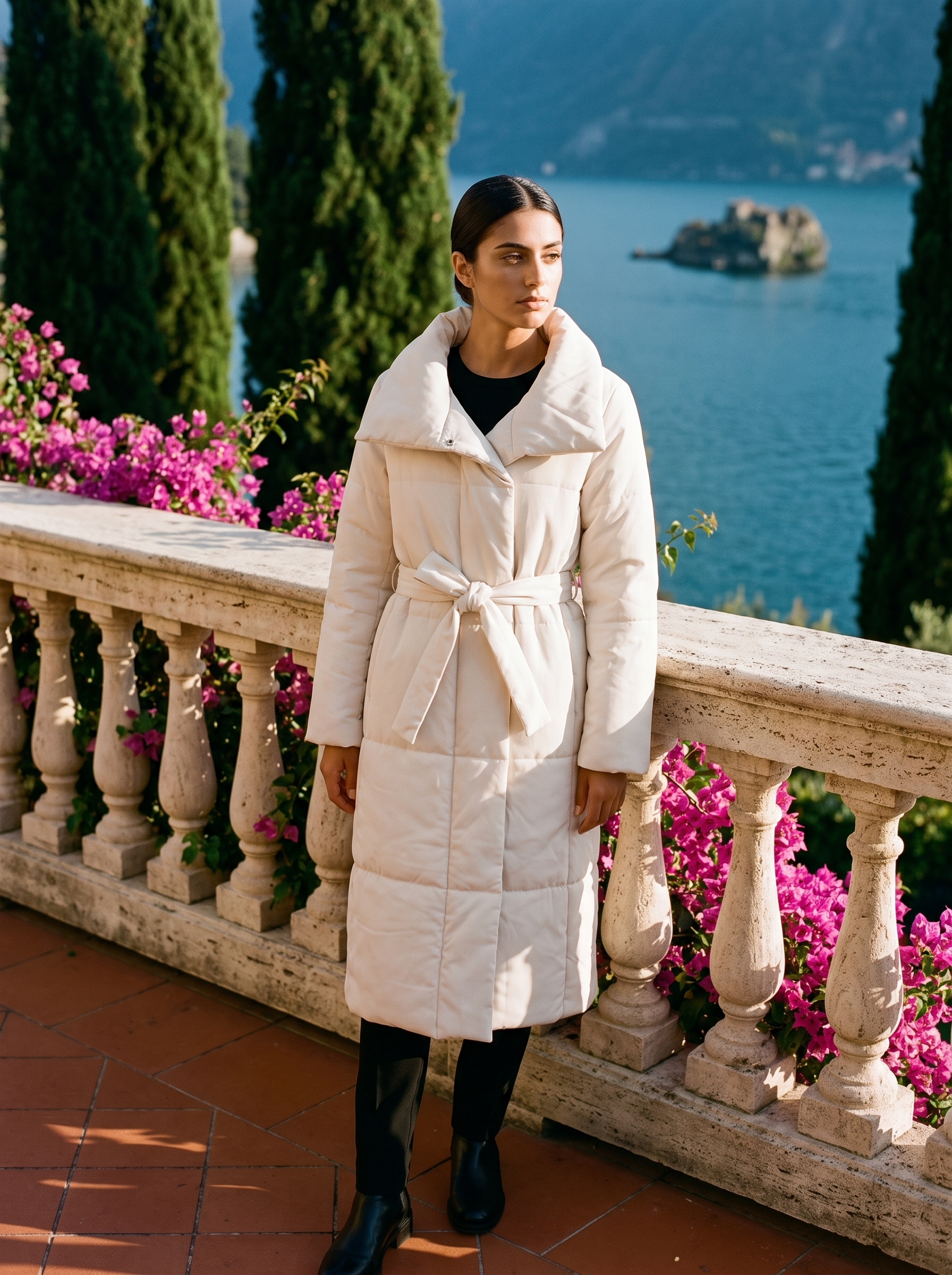 Full-length front view of a cream belted quilted coat on a Lake Como terrace — Aveloire
