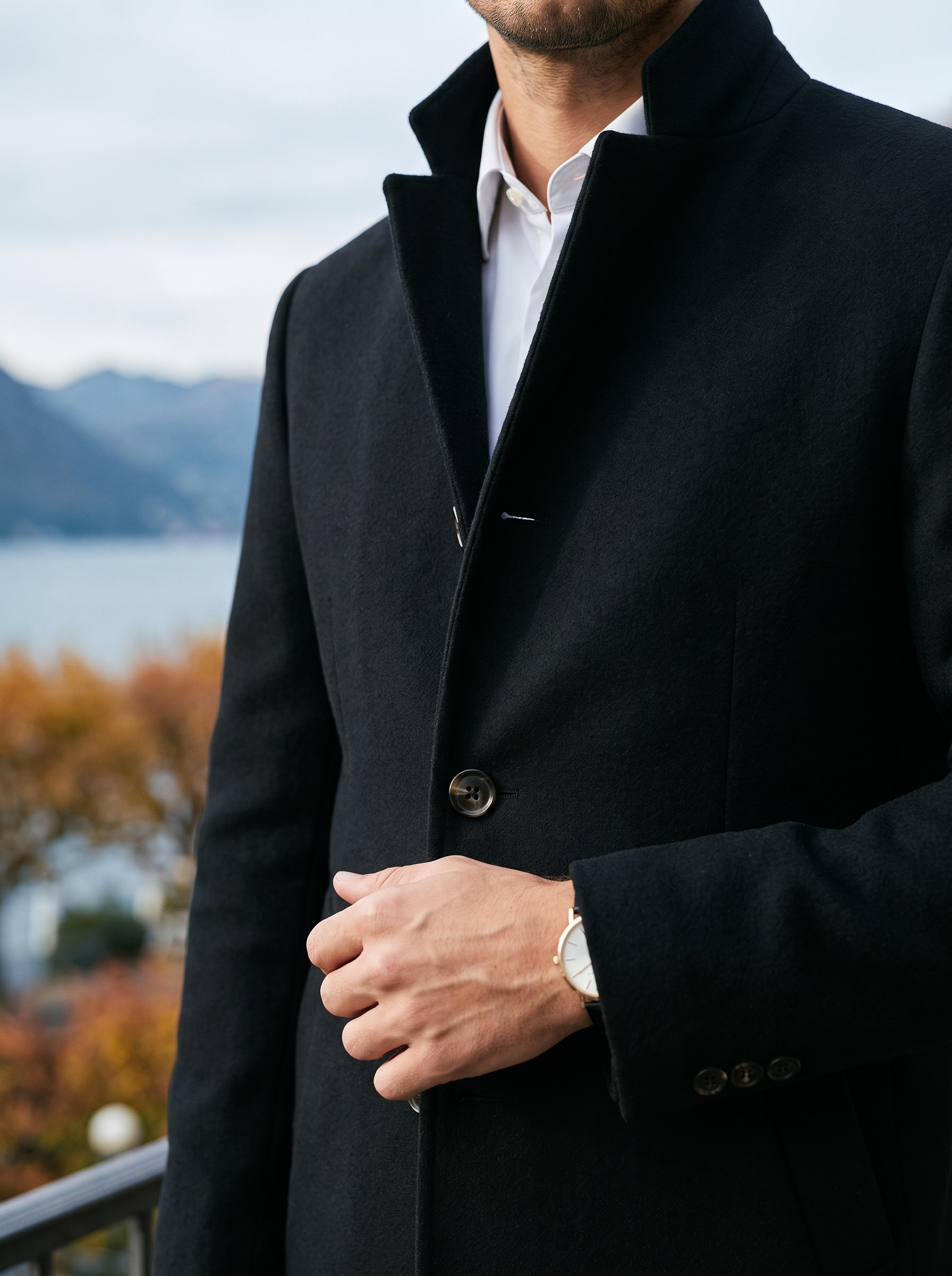 Close-up of the stand collar and button front on the black overcoat — Aveloire