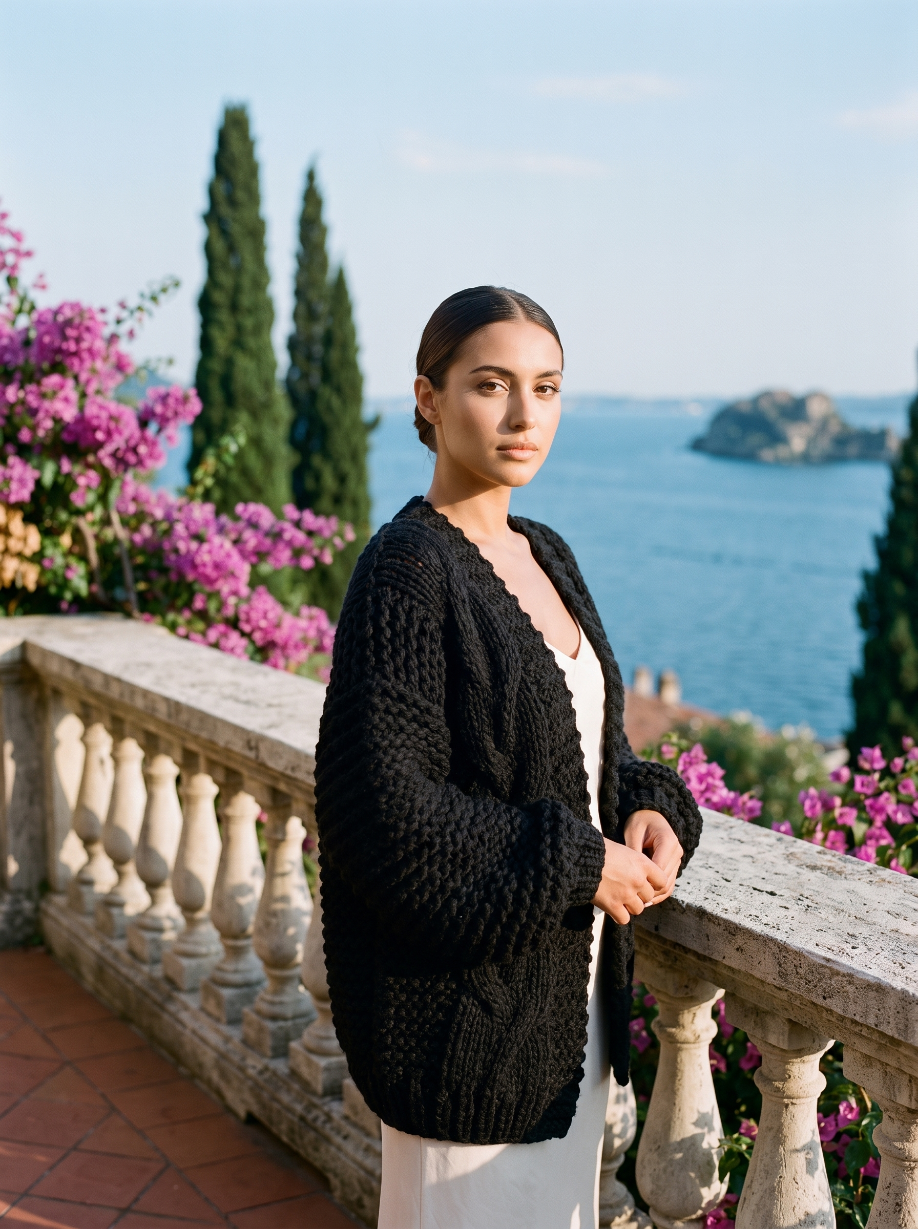 Woman wearing a black chunky knit open-front cardigan on a Lake Como terrace — Aveloire
