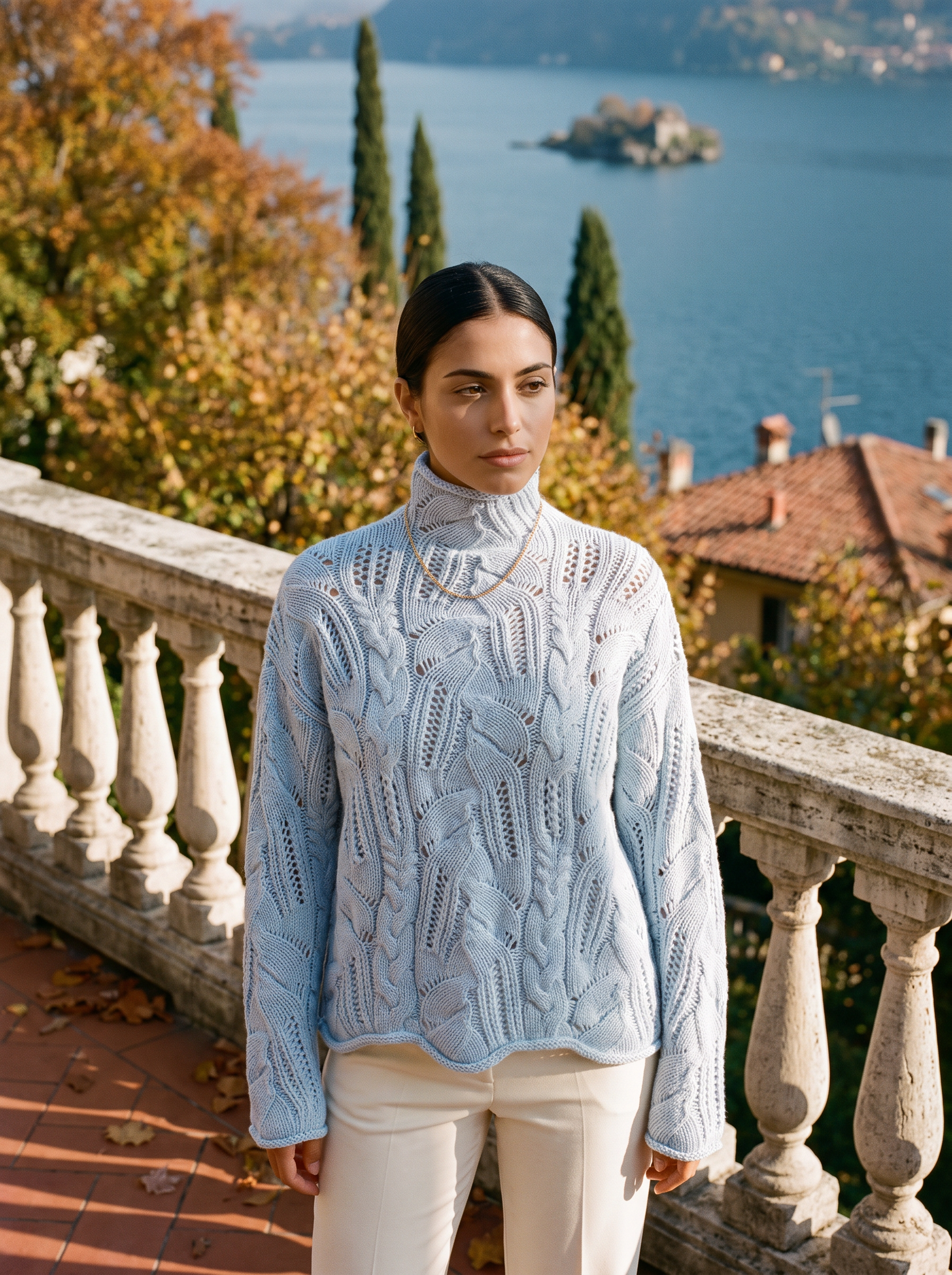 Woman wearing a light blue pointelle openwork turtleneck sweater on a terrace by Lake Como — Aveloire