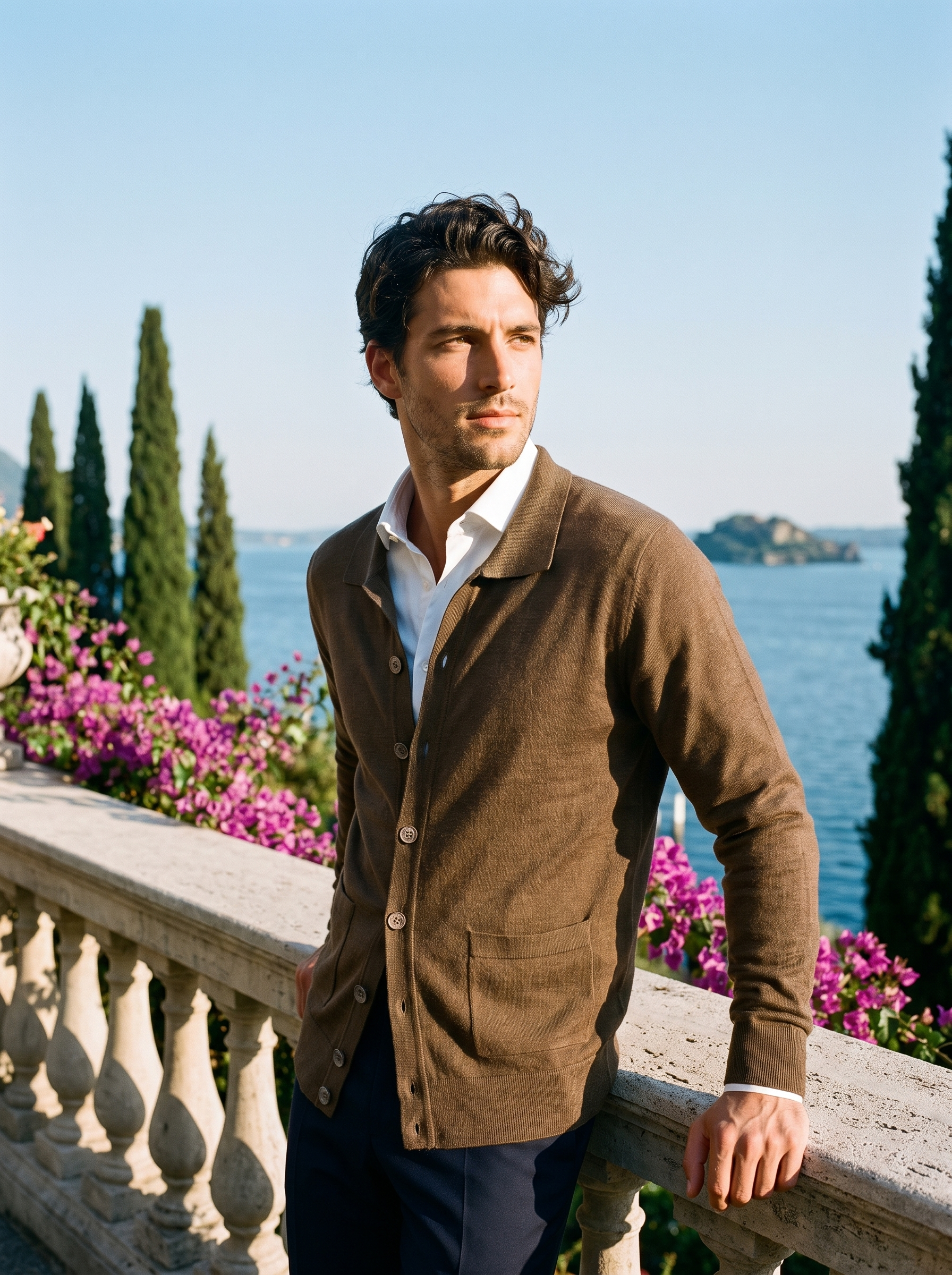 Man wearing a brown button-up collared cardigan on a terrace overlooking Lake Como, old money style — Aveloire