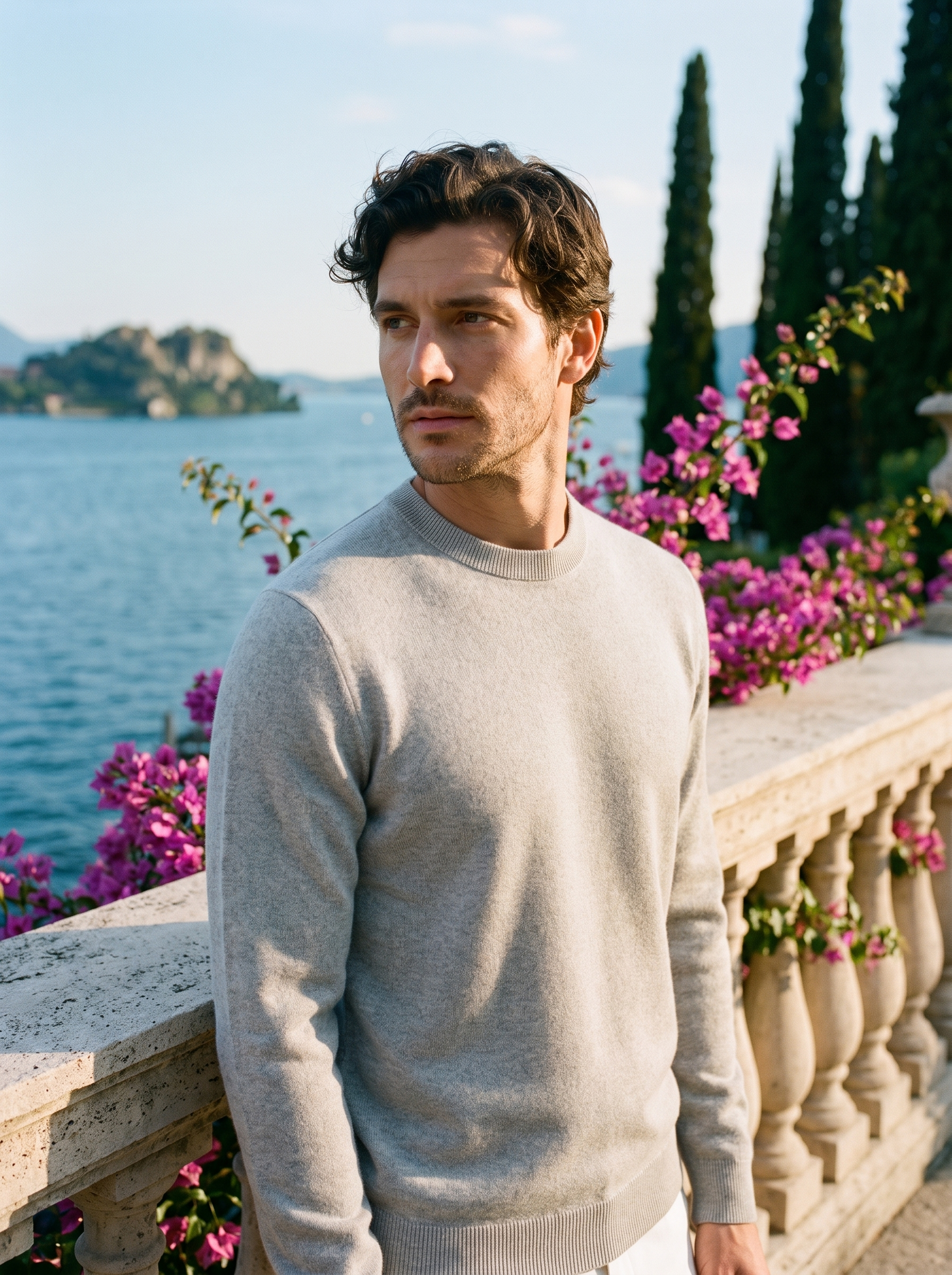 Man wearing a light gray 100% wool crewneck sweater on a terrace overlooking Lake Como, old money style — Aveloire
