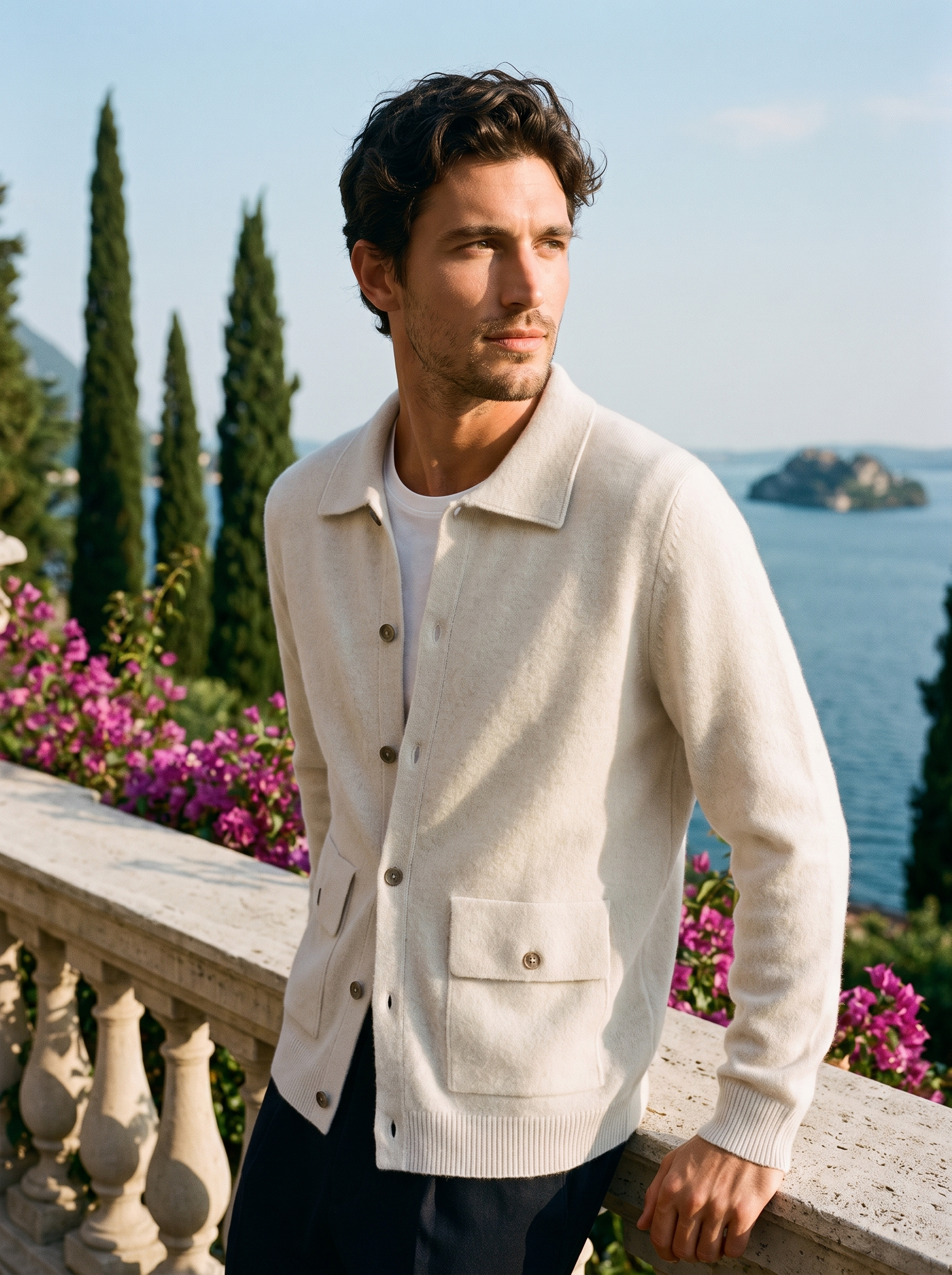 Man wearing a white 100% cashmere collared cardigan on a terrace overlooking Lake Como, old money style — Aveloire