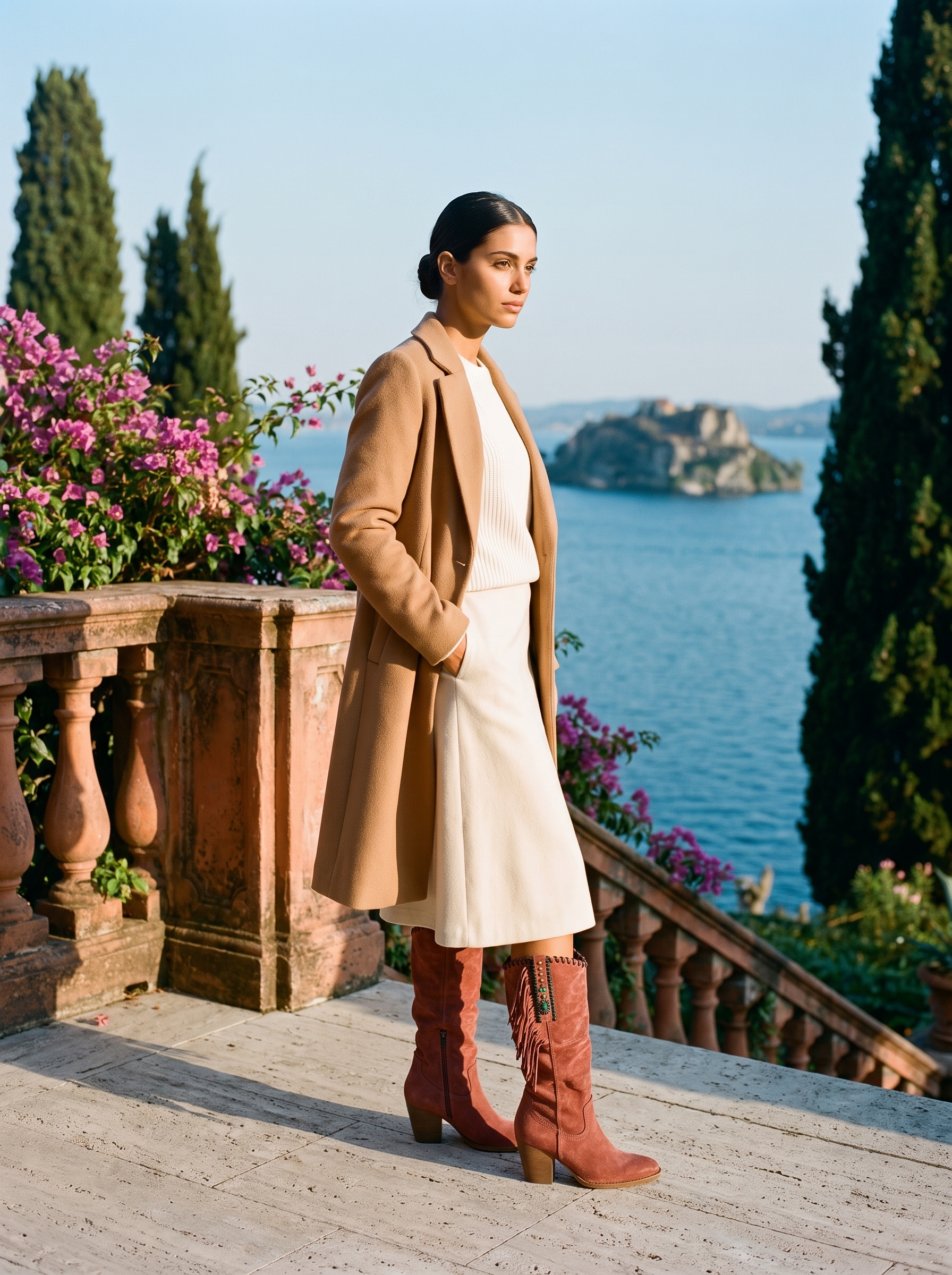 Full body front view of red fringed western knee high boots with cream midi skirt and camel coat — Aveloire