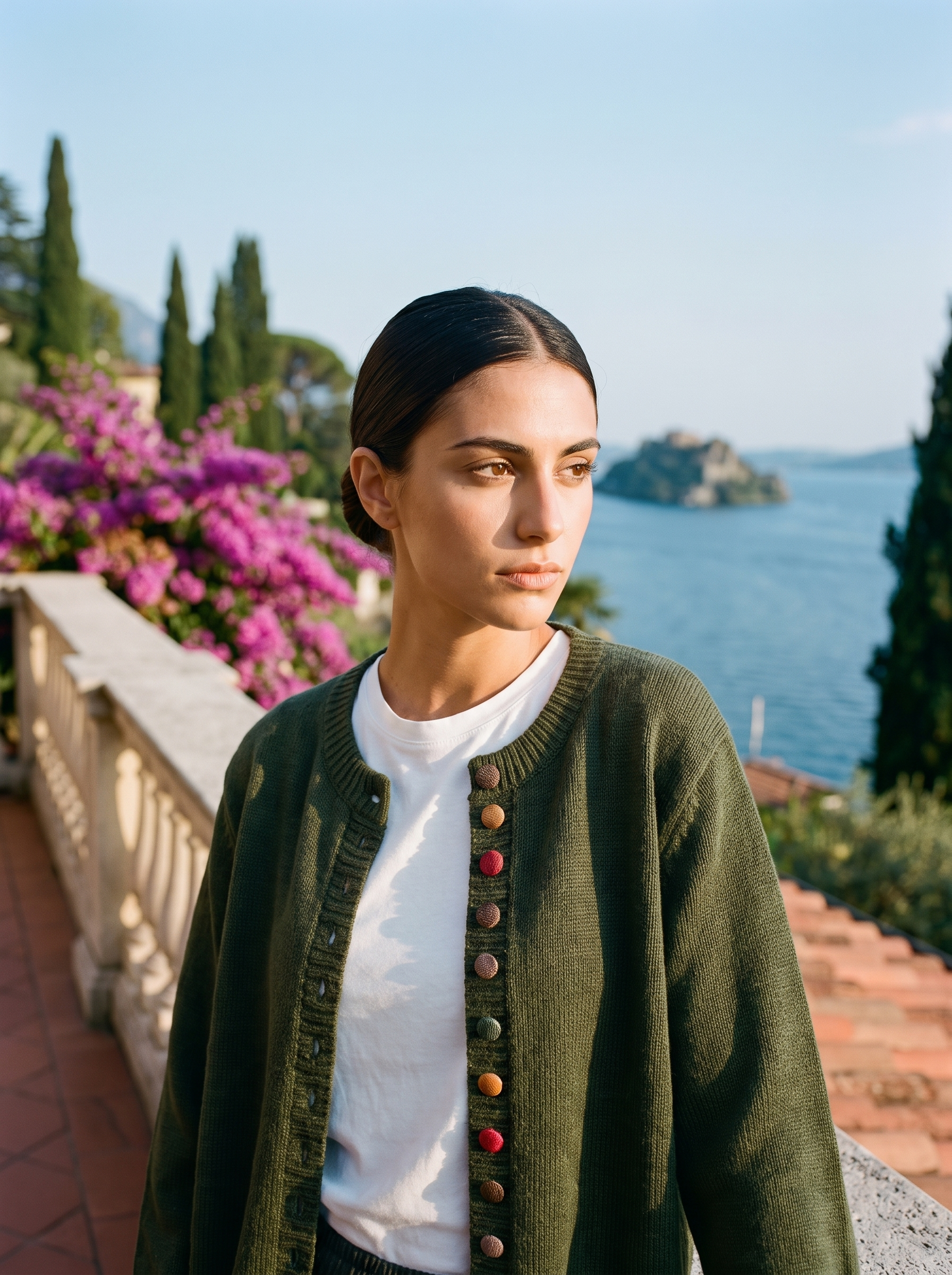 Woman wearing an army green button cardigan on a terrace overlooking Lake Como, old money style — Aveloire