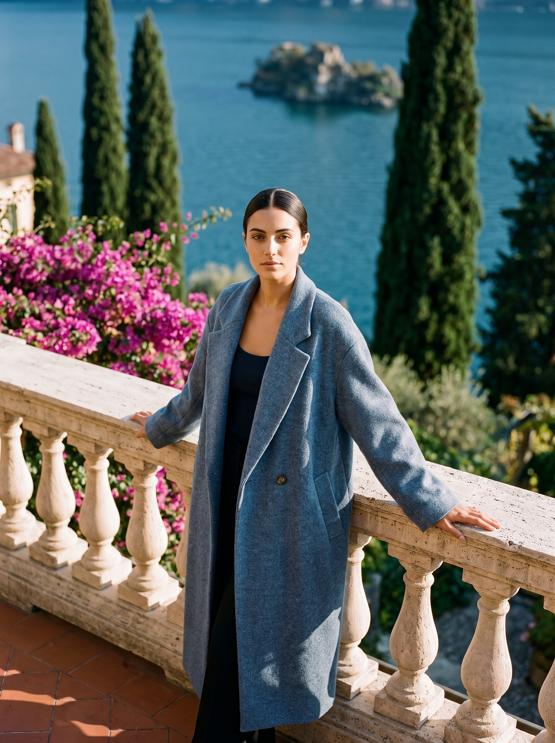 Woman wearing slate blue oversized longline wool coat on a Lake Como terrace
