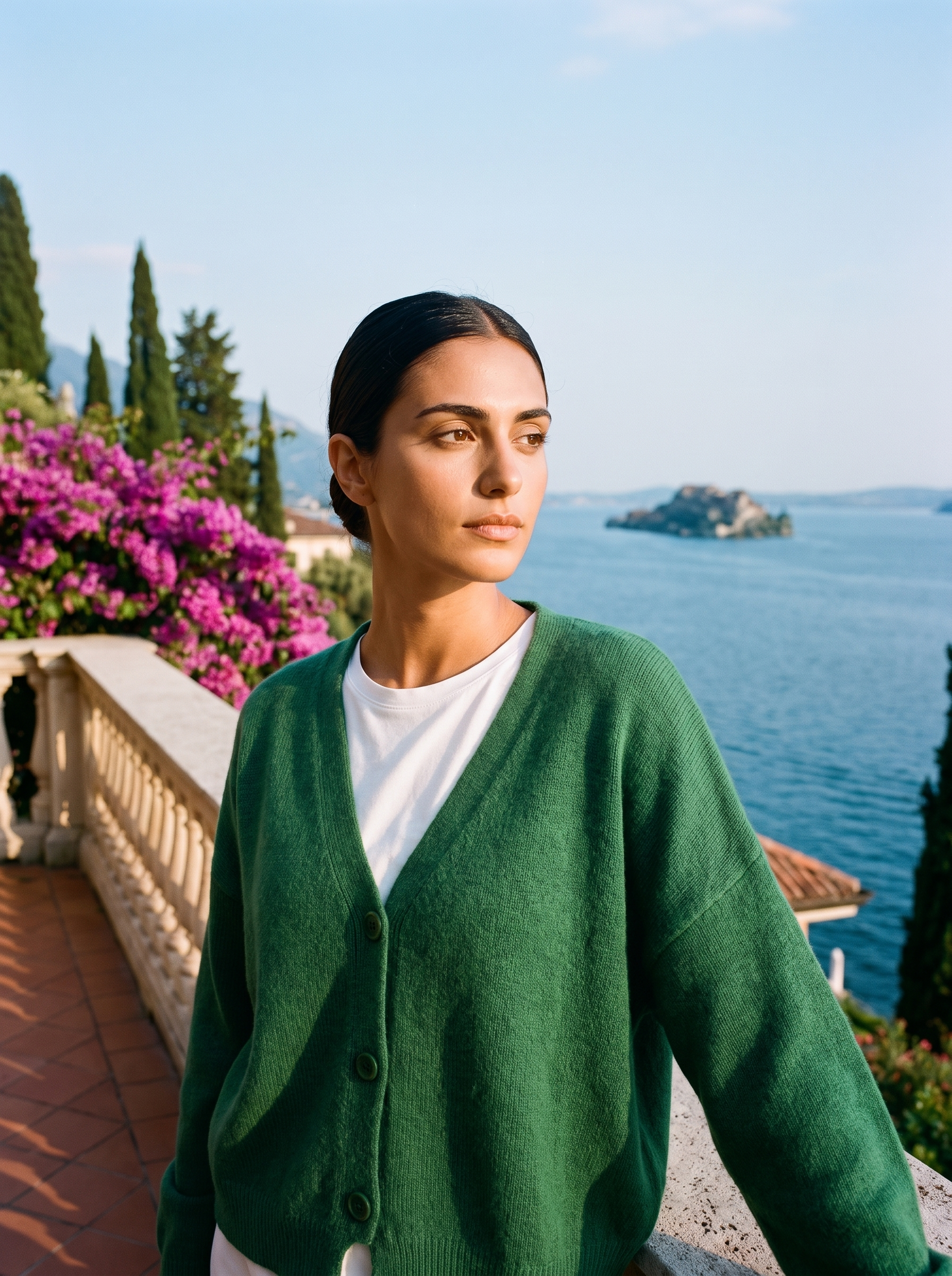 Woman wearing a green V-neck cardigan on a terrace overlooking Lake Como, old money style — Aveloire