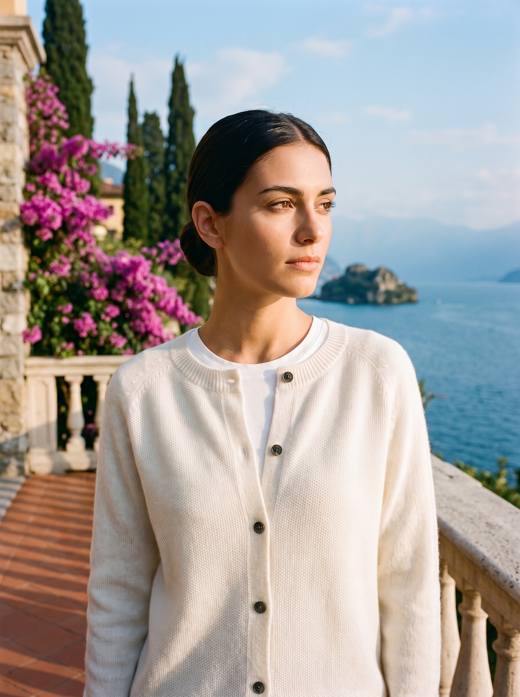 Woman wearing a white wool-blend cardigan on a terrace overlooking Lake Como, old money style — Aveloire