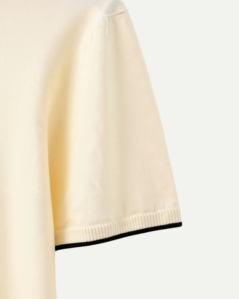 Close-up of beige knit polo short sleeve with black contrast trim edge