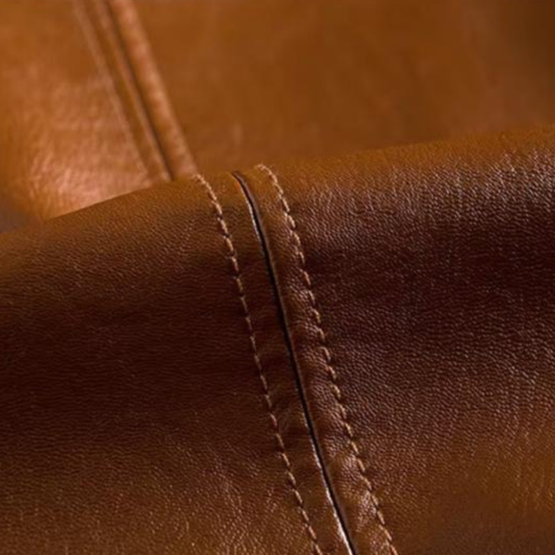 Close-up of the leather grain and topstitched seam on the cognac blazer jacket — Aveloire