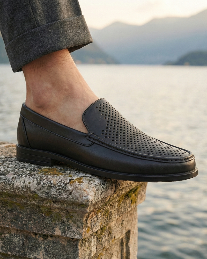 Men’s black leather slip-on loafers styled on feet with tailored trousers