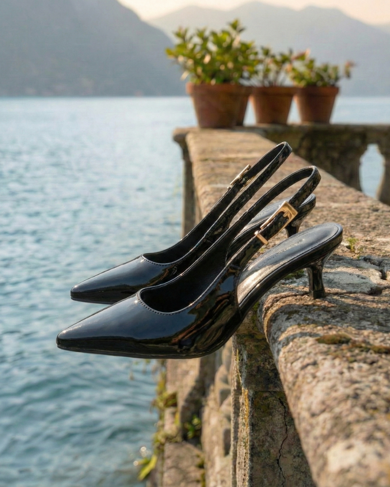 Women’s black patent pointed toe slingback pumps displayed on terrace