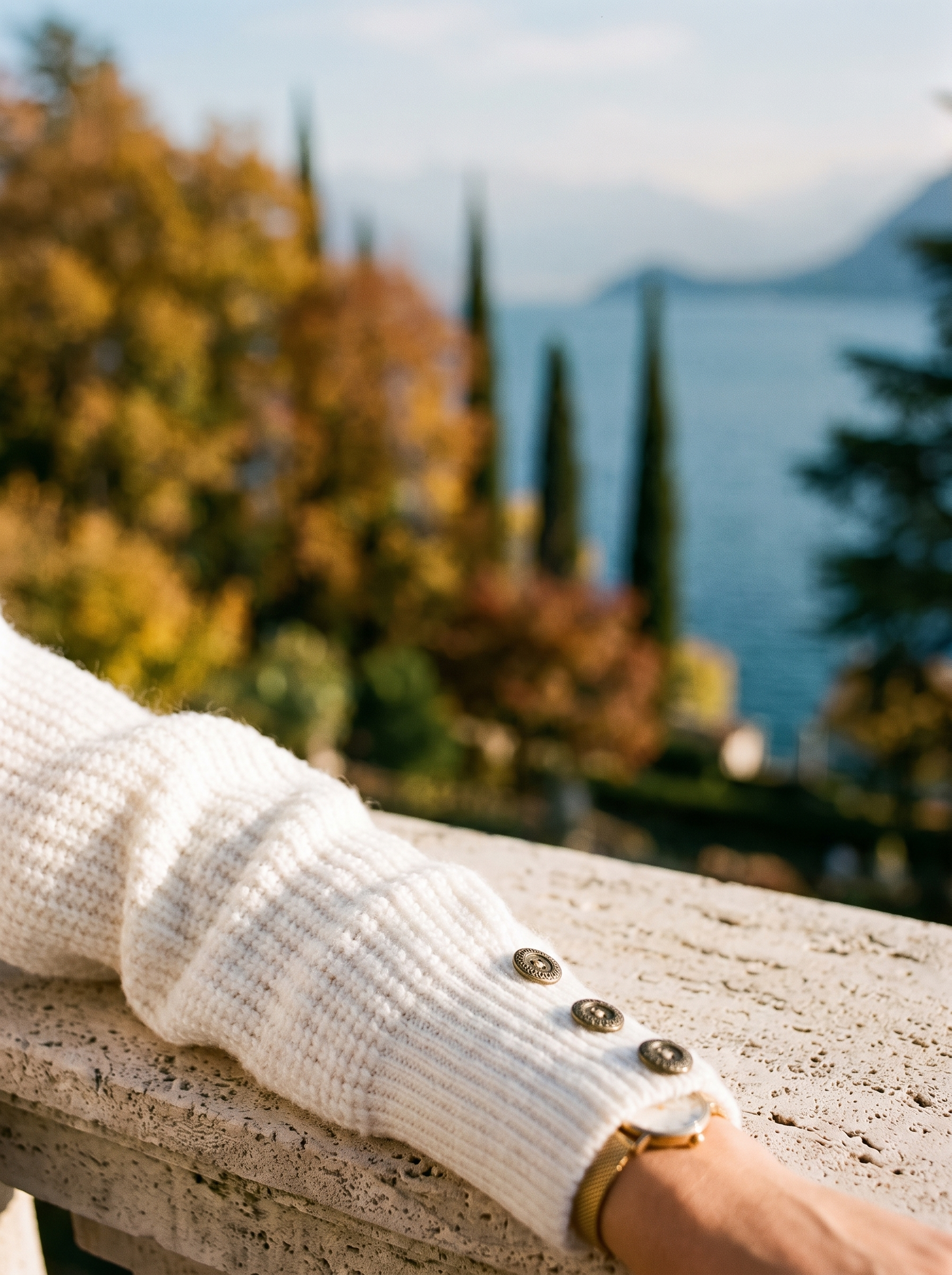 Close-up of the ribbed cuff and decorative buttons on a white chunky knit sweater - Aveloire