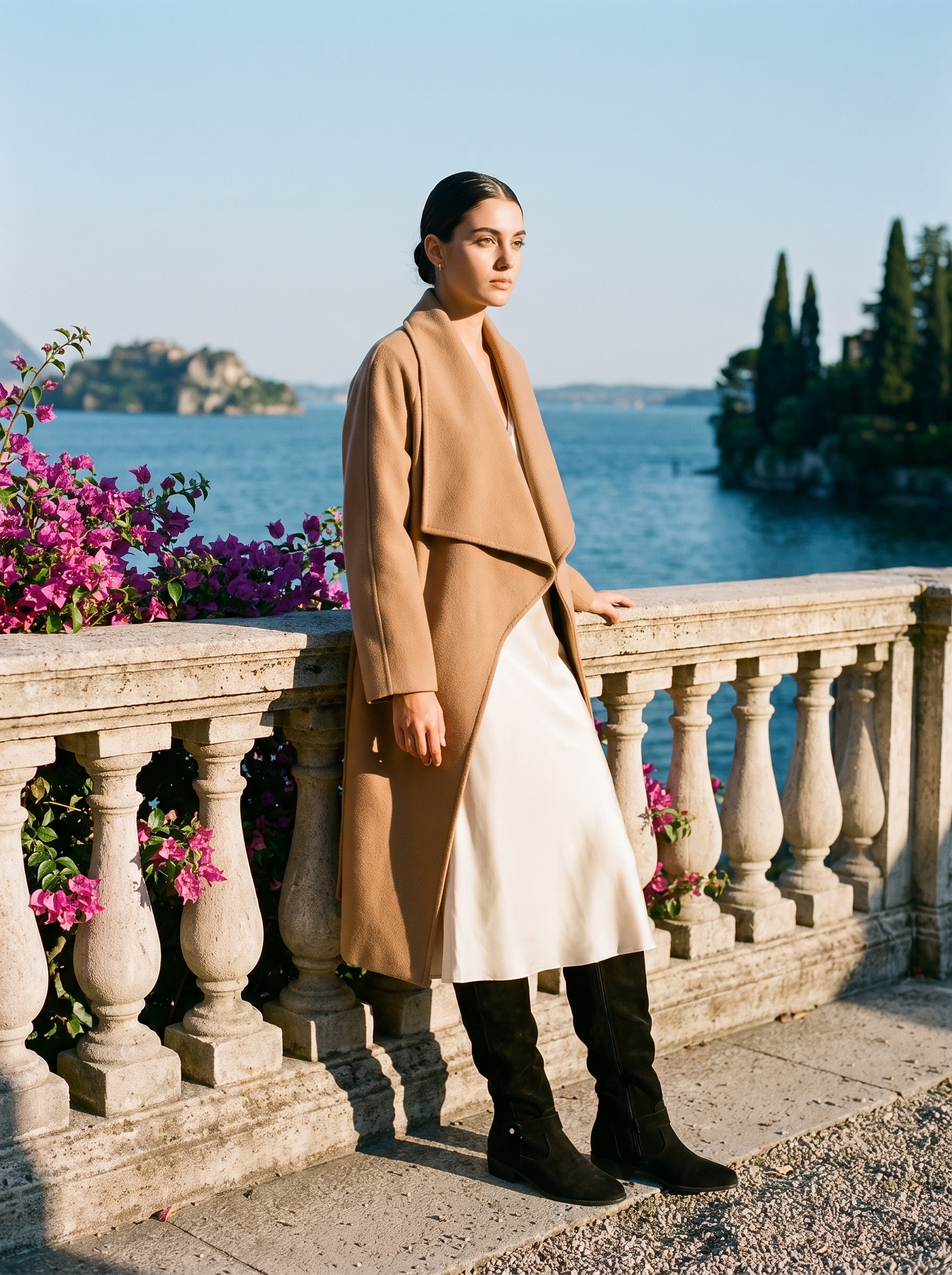 Full body front view of a woman in black buckled slouch knee high boots and a cream skirt on a Lake Como terrace — Aveloire