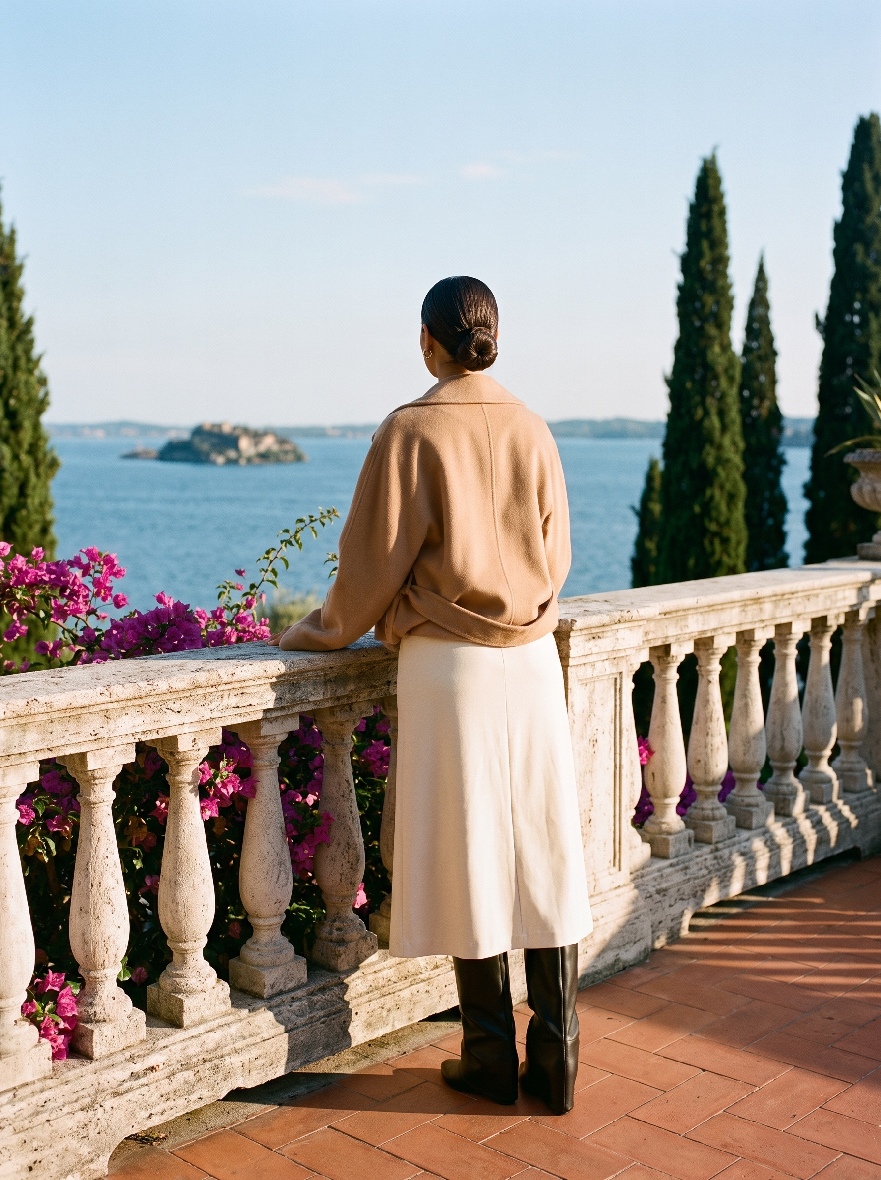 Back view of black fold-over knee high boots showing the folded cuff and low wedge heel on a Lake Como terrace — Aveloire