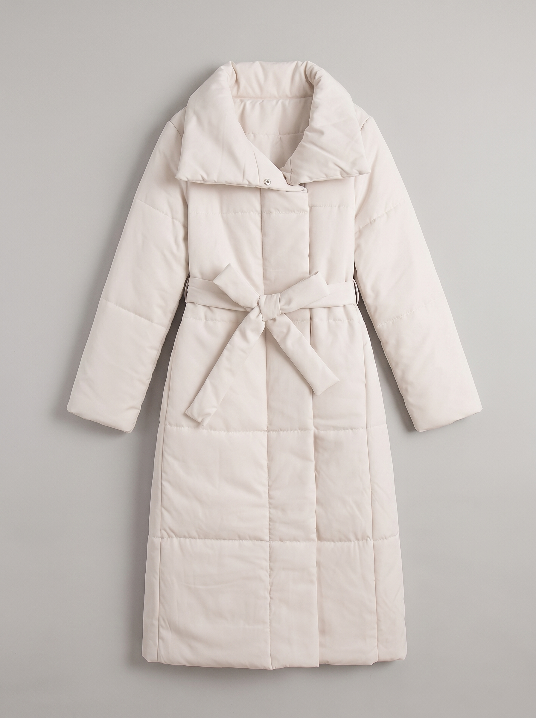 Cream longline belted quilted coat flat lay product photo — Fenice by Aveloire