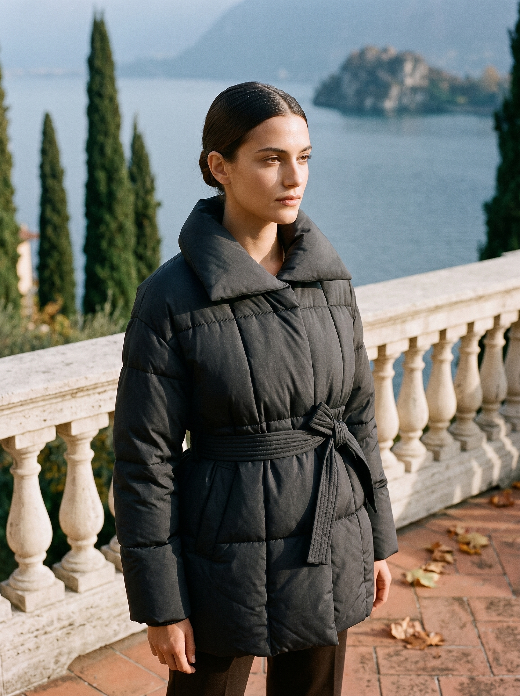 Black belted quilted coat for women, worn on a Lake Como terrace — Aveloire