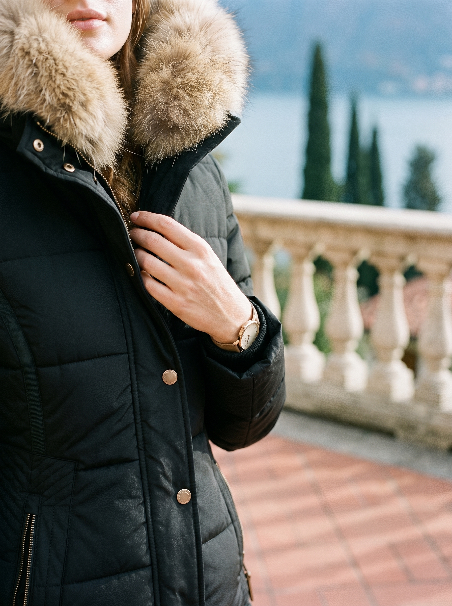 Close-up of the faux fur hood and gold-tone snap placket on the black puffer coat — Aveloire