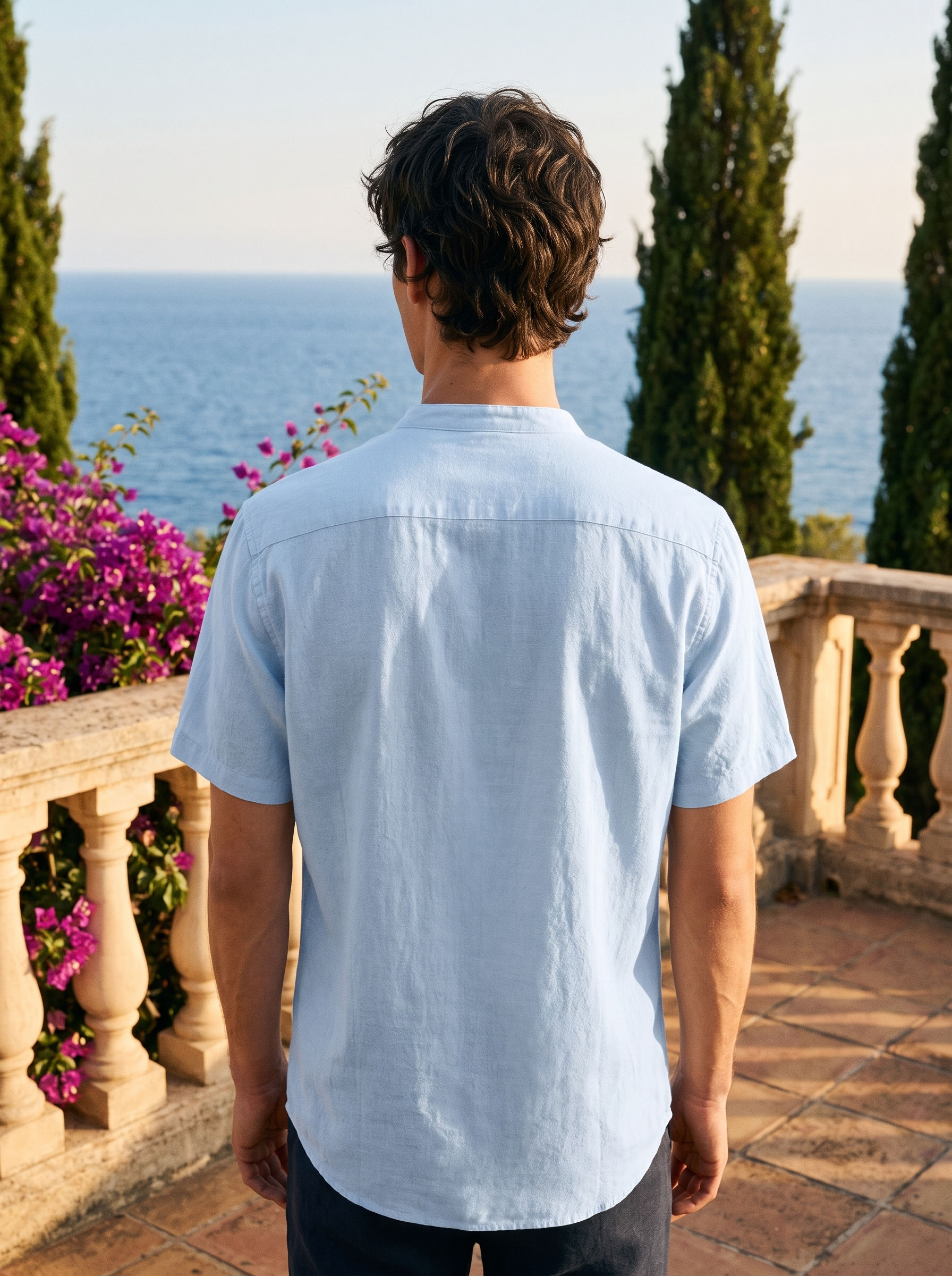 Back view of a man in a sky blue band-collar linen shirt overlooking Lake Como — Aveloire