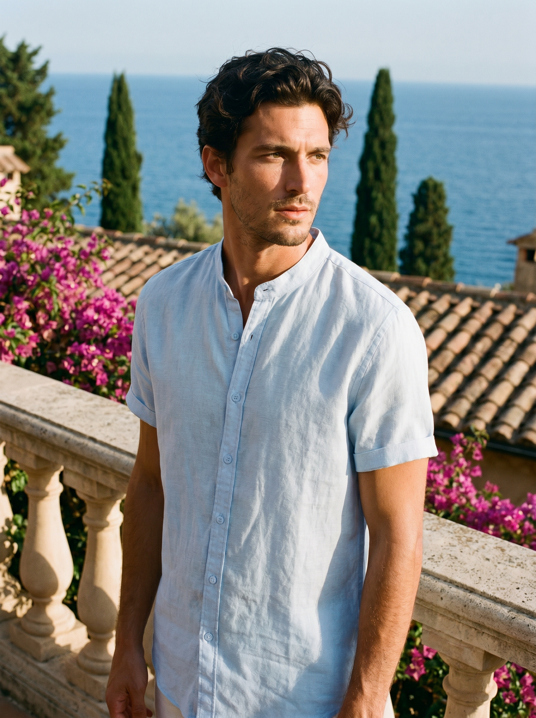 Man wearing a pastel blue band-collar linen shirt on a balcony overlooking Lake Como, old money summer style — Aveloire