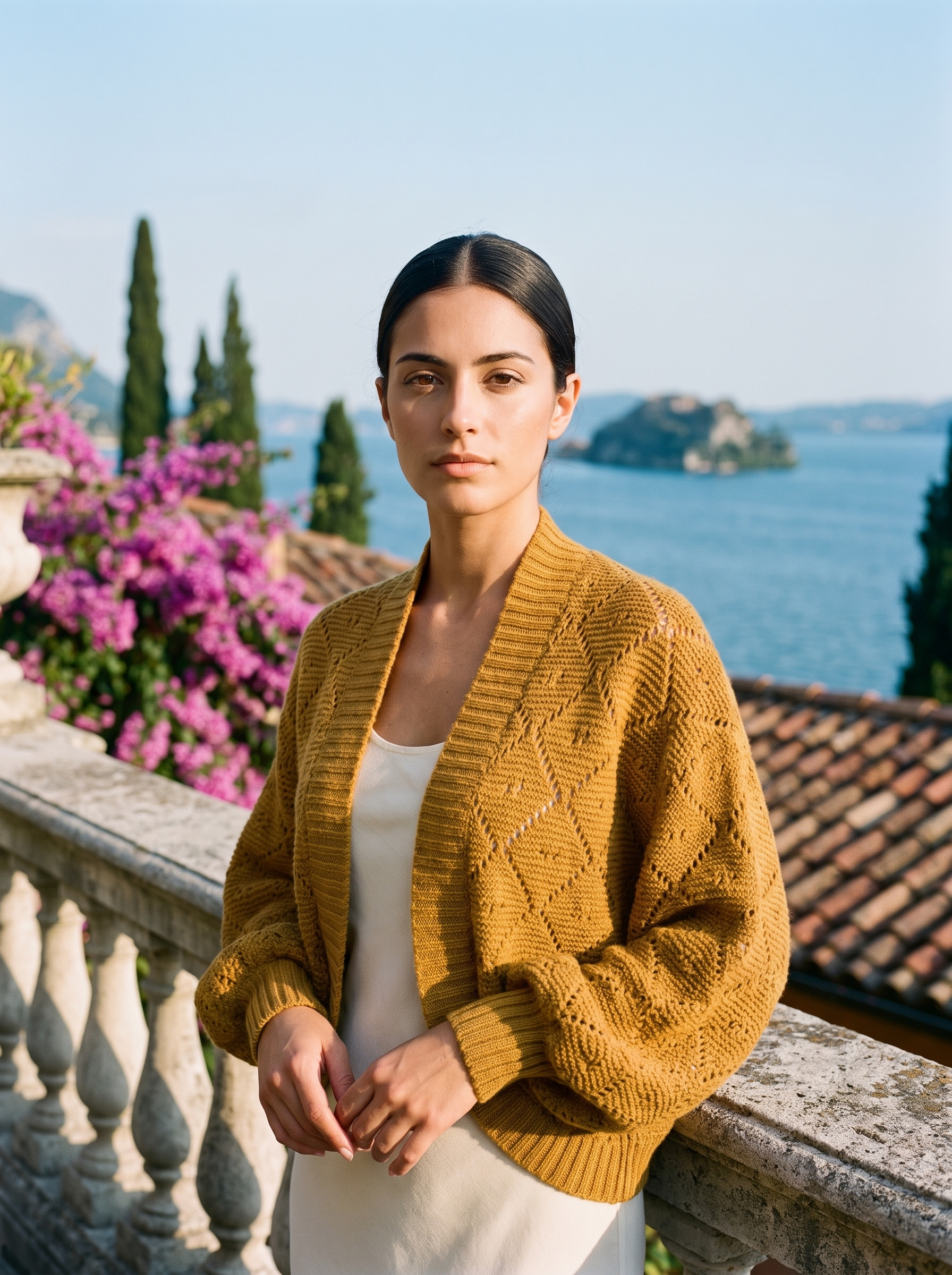 Woman wearing a mustard cropped open-front knit shrug cardigan on a Lake Como terrace — Aveloire