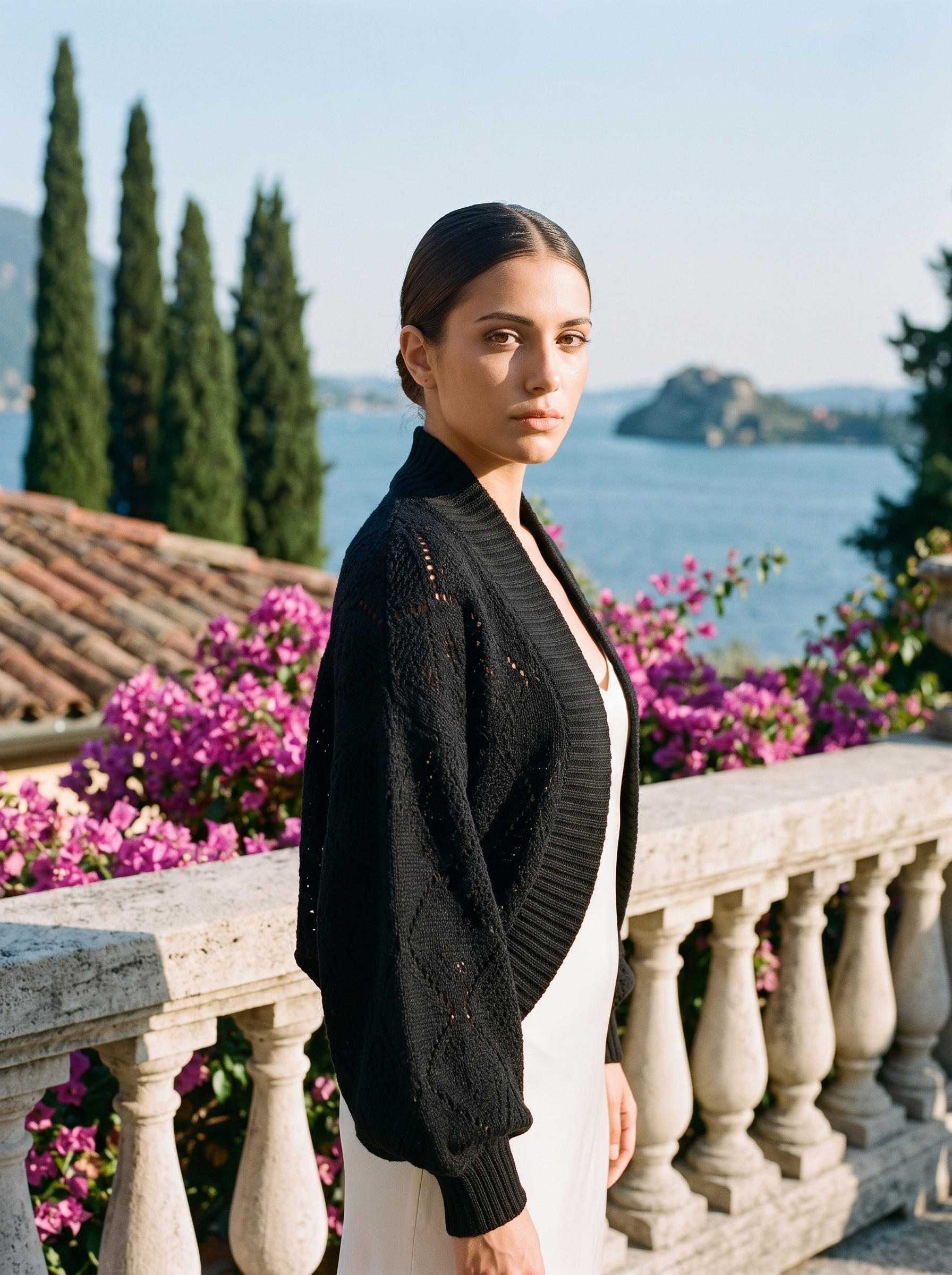 Woman wearing a black cropped open-front knit shrug cardigan on a Lake Como terrace — Aveloire
