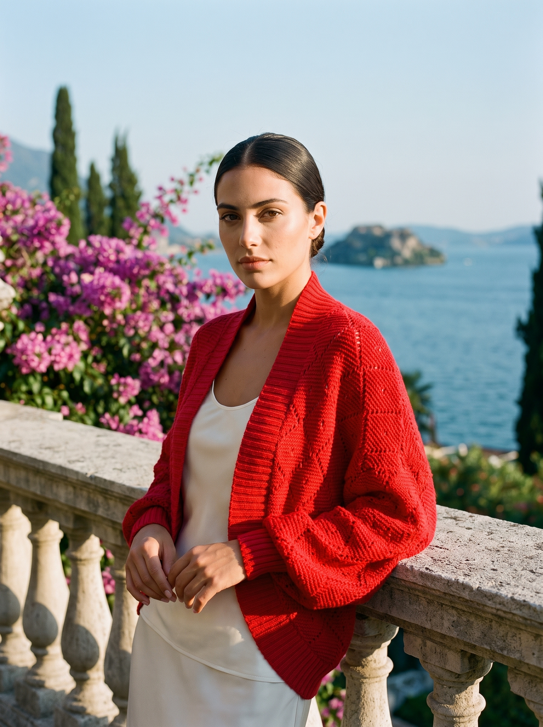 Woman wearing a red cropped open-front knit shrug cardigan on a Lake Como terrace — Aveloire