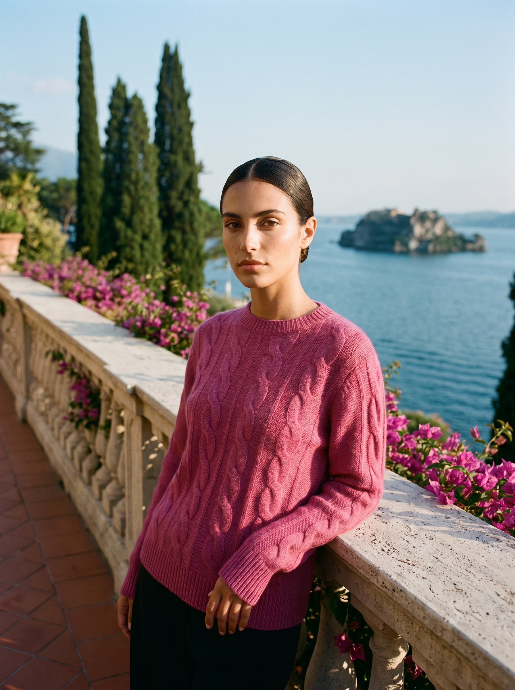 Woman wearing a raspberry pink cable-knit crew neck sweater on a Lake Como terrace — Aveloire