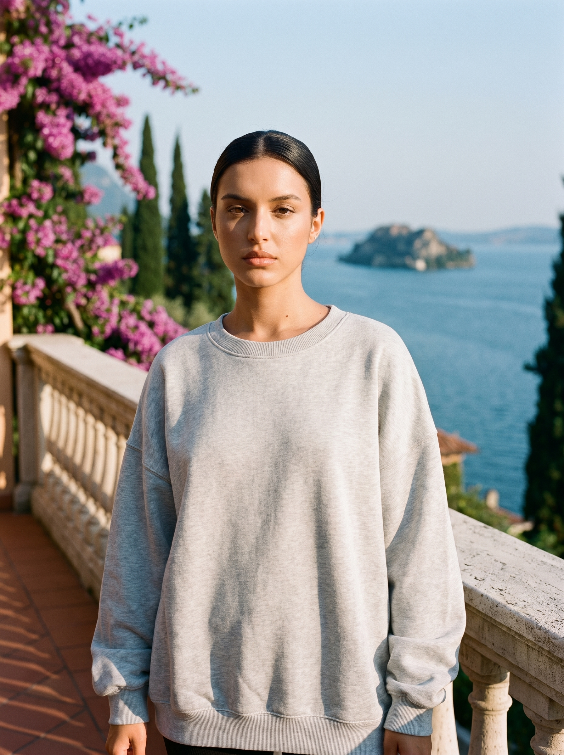 Woman wearing a light grey oversized crew neck sweatshirt on a Lake Como terrace, old money style — Aveloire