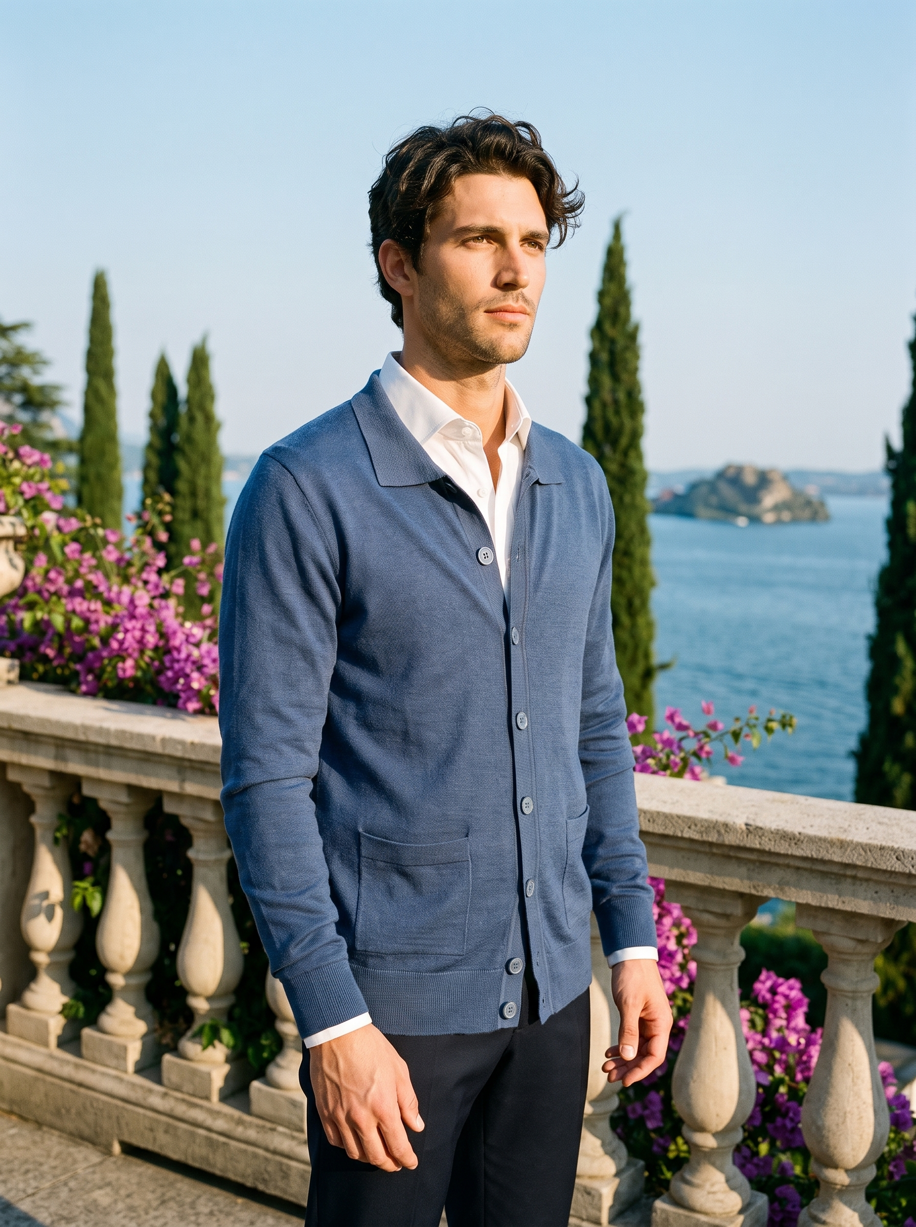 Man wearing a blue button-up collared cardigan on a terrace overlooking Lake Como, old money style — Aveloire