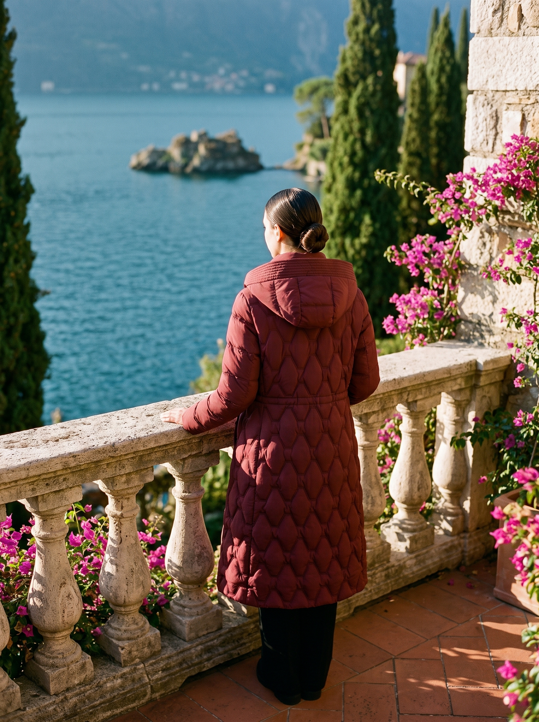 Wine red onion-quilted longline hooded puffer coat back view at balustrade