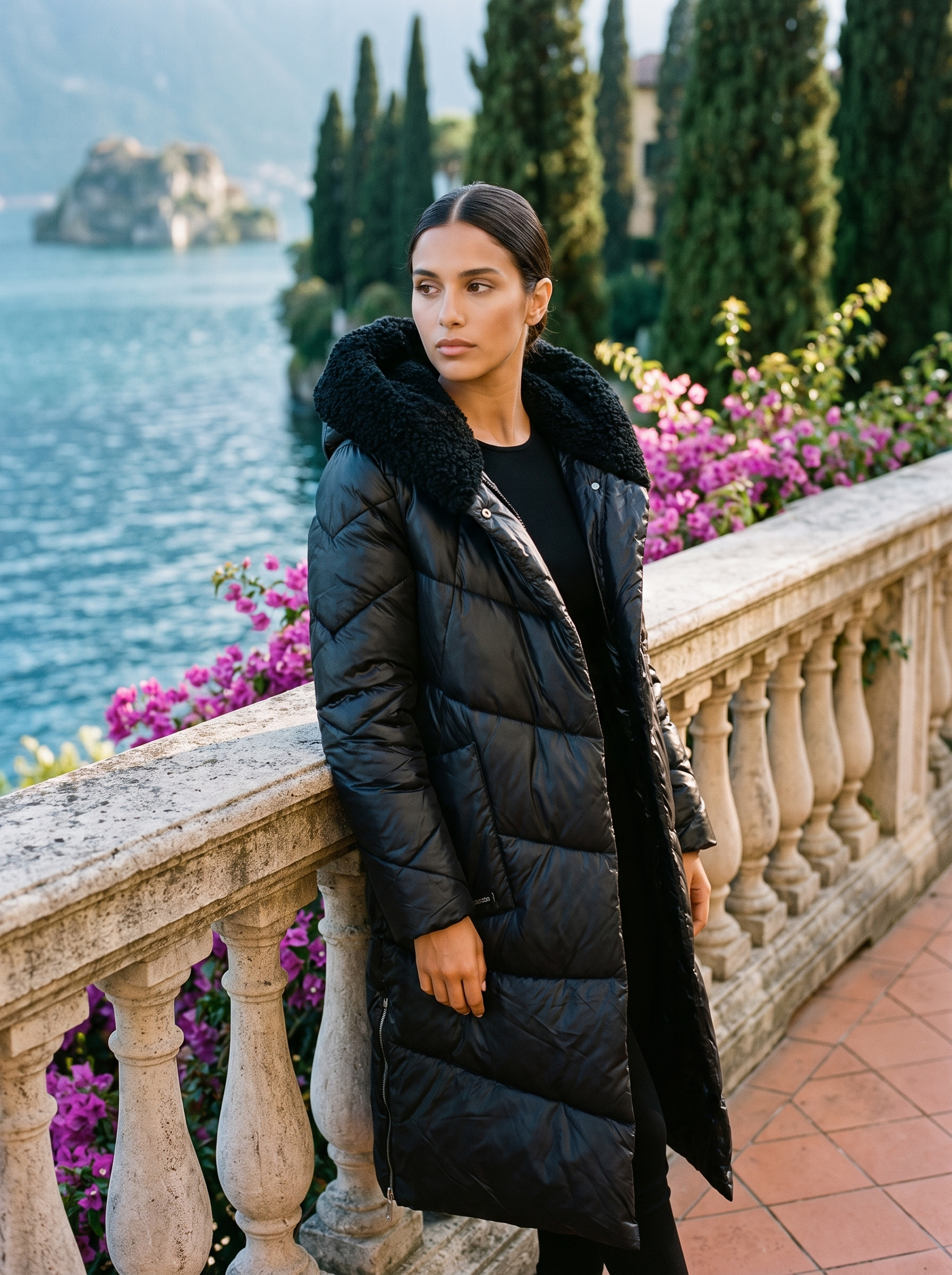 Woman wearing a black quilted hooded puffer coat on a Lake Como terrace — Aveloire