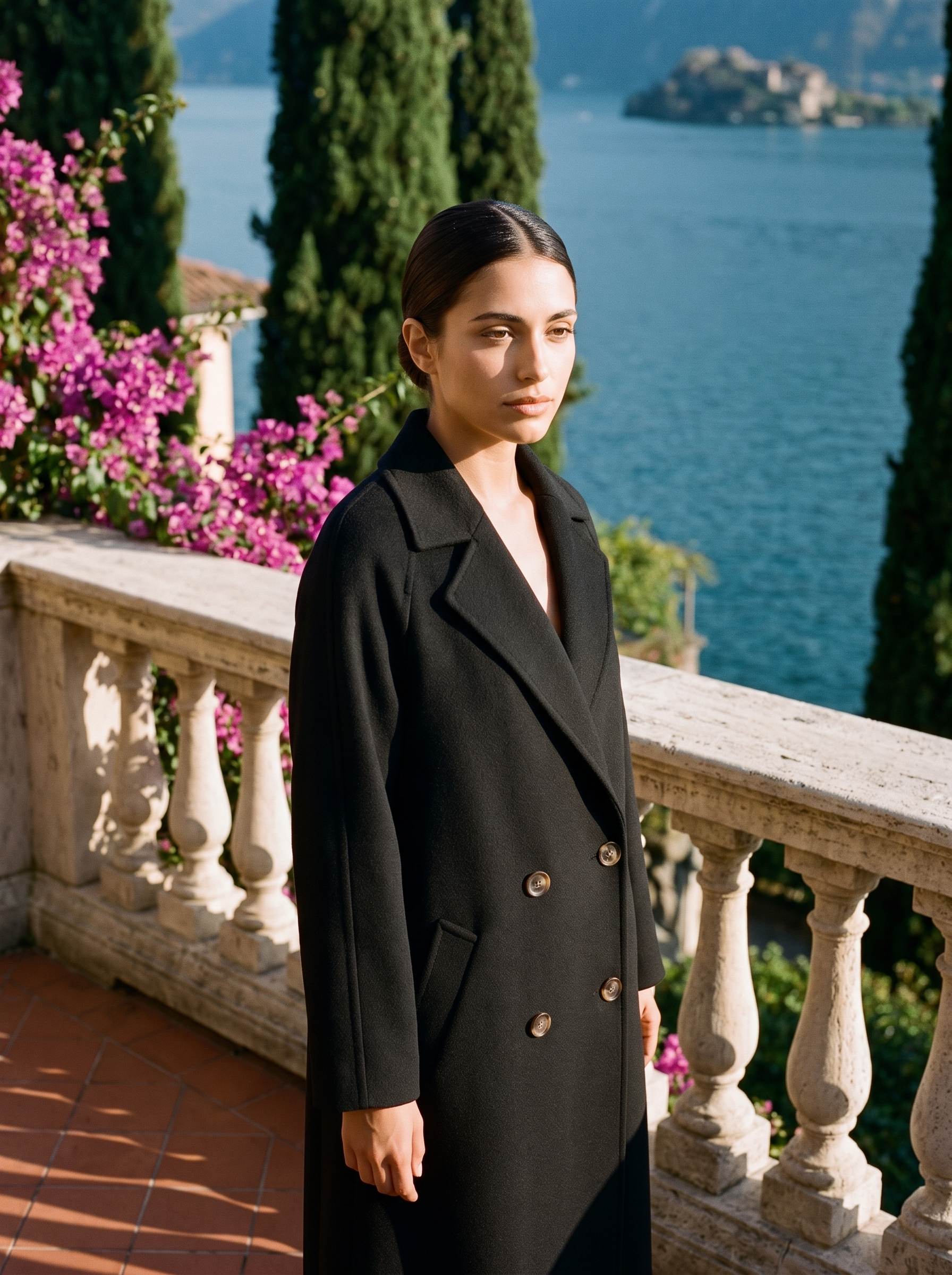 Woman wearing black double-breasted wool coat on a Lake Como terrace