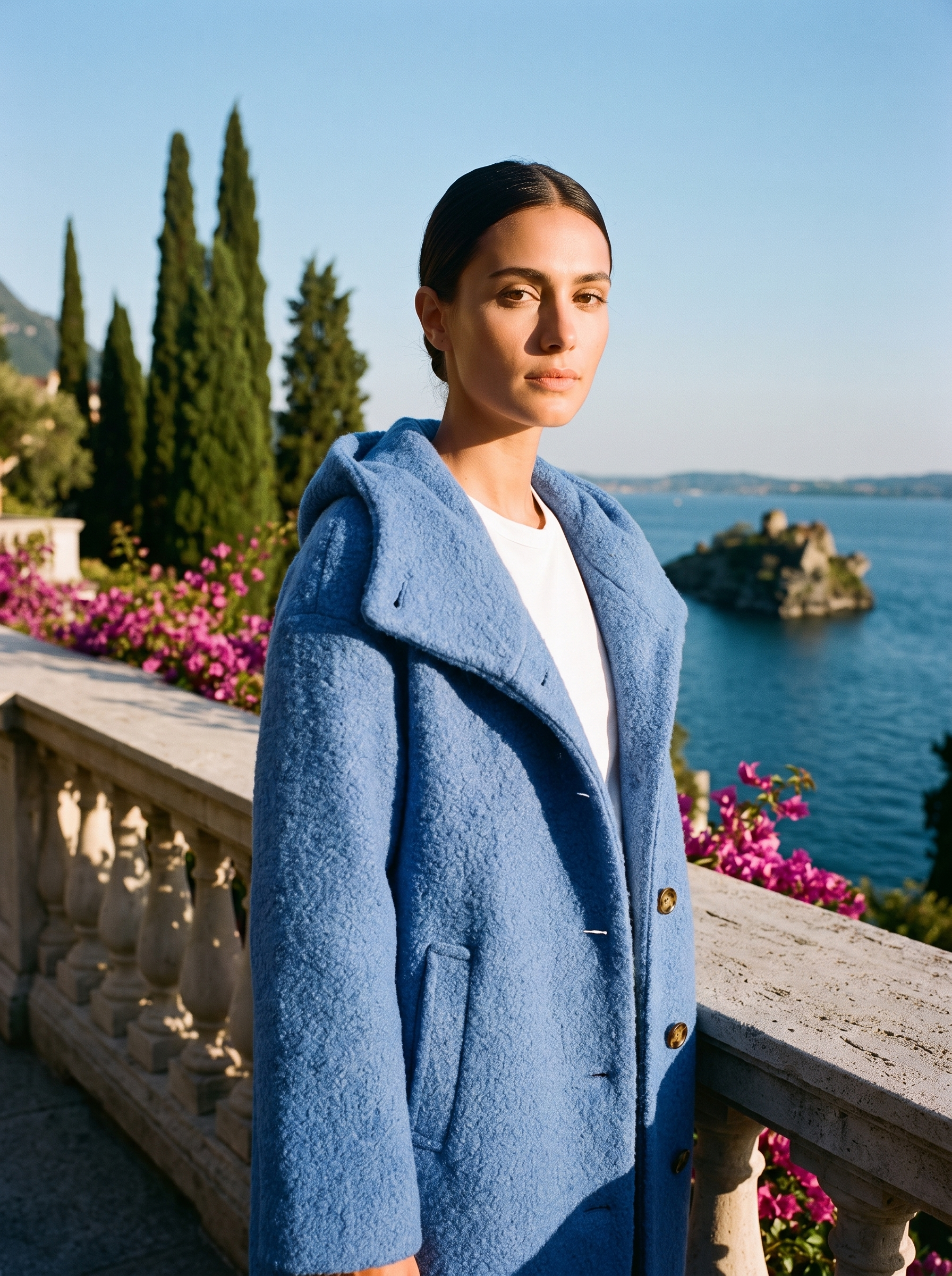 Woman wearing a blue hooded wool coat on a terrace overlooking Lake Como — Aveloire