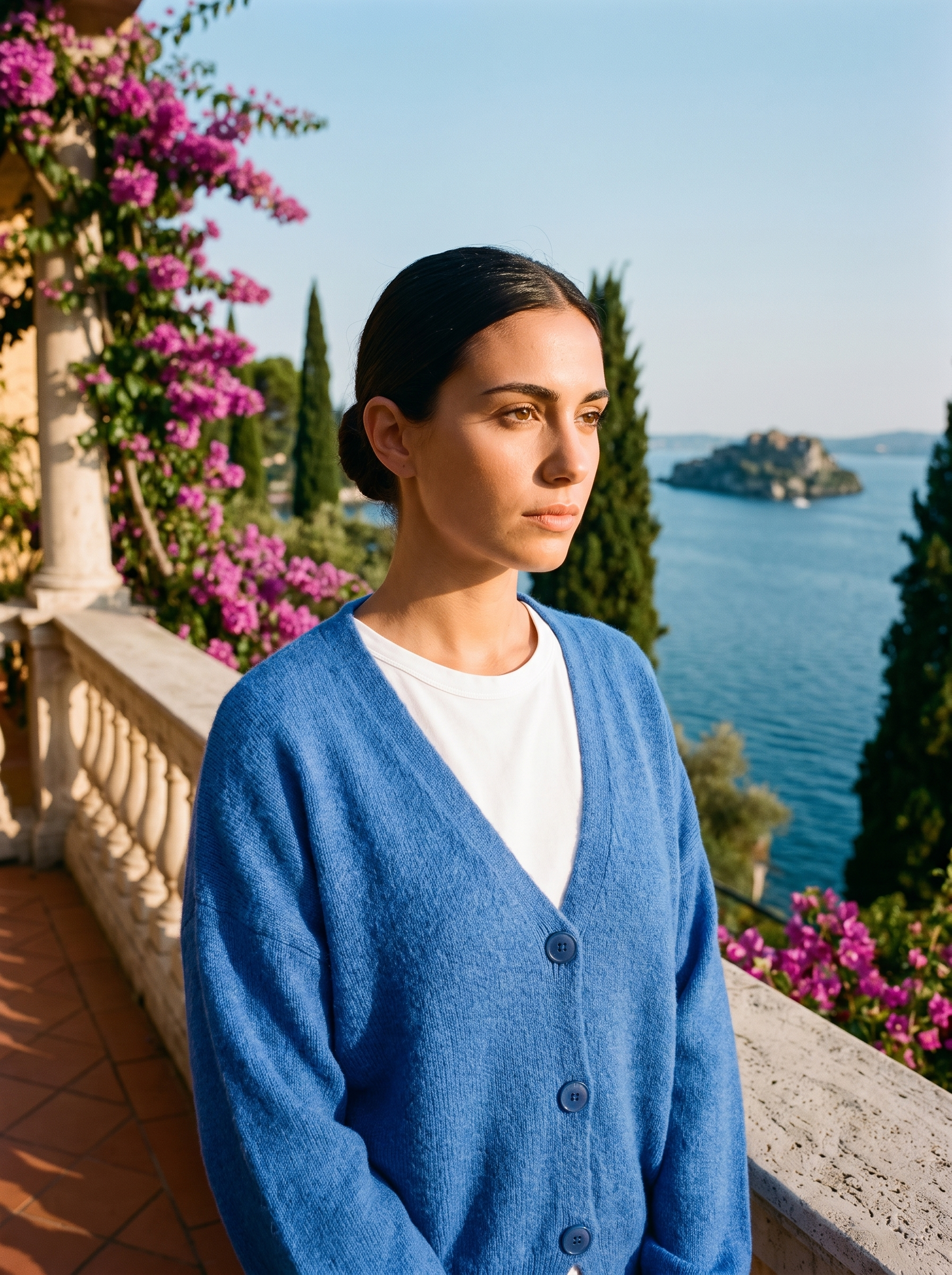 Woman wearing a blue V-neck cardigan on a terrace overlooking Lake Como, old money style — Aveloire