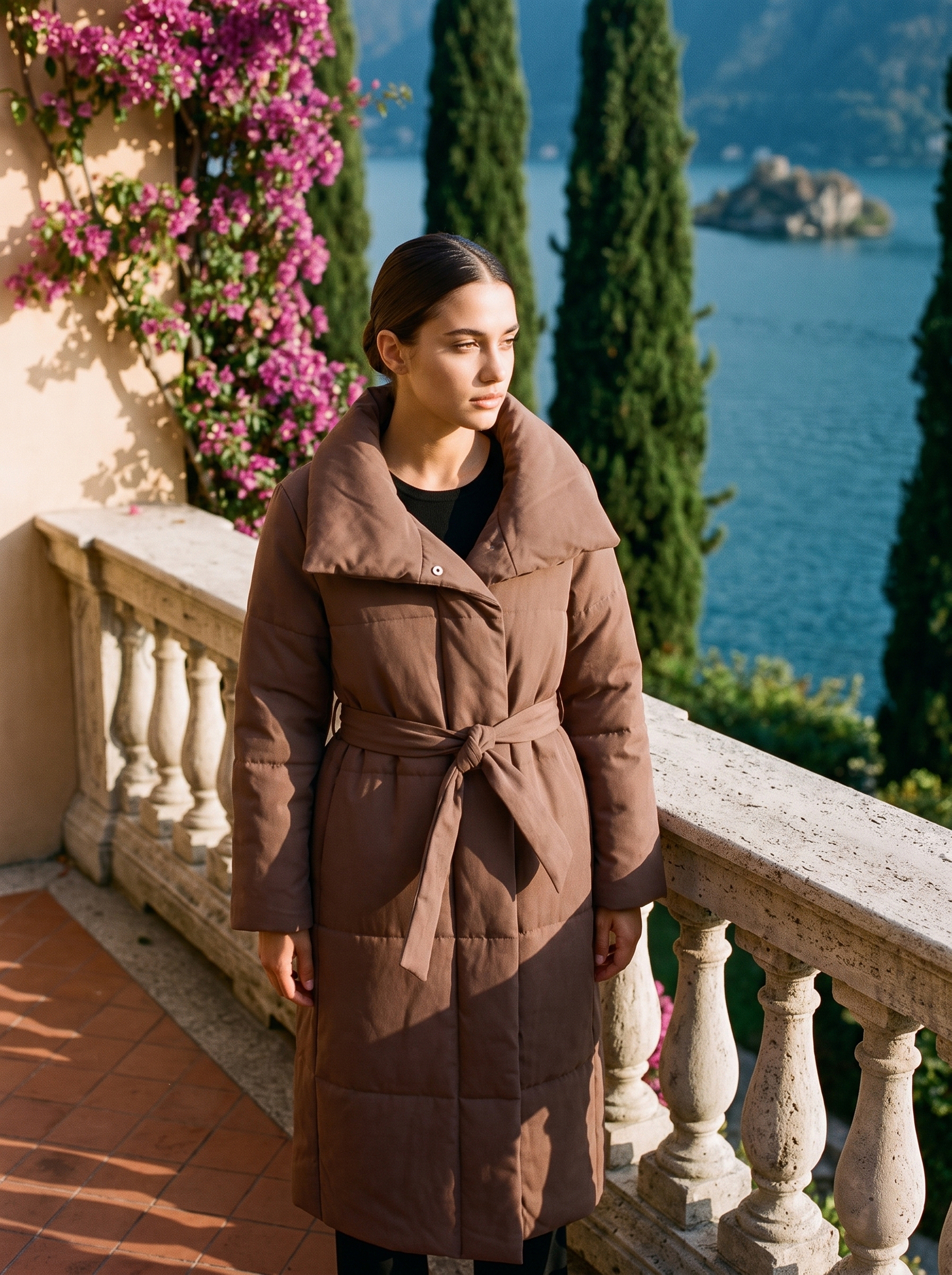 Woman wearing a mocha-brown belted quilted coat on a Lake Como terrace — Aveloire