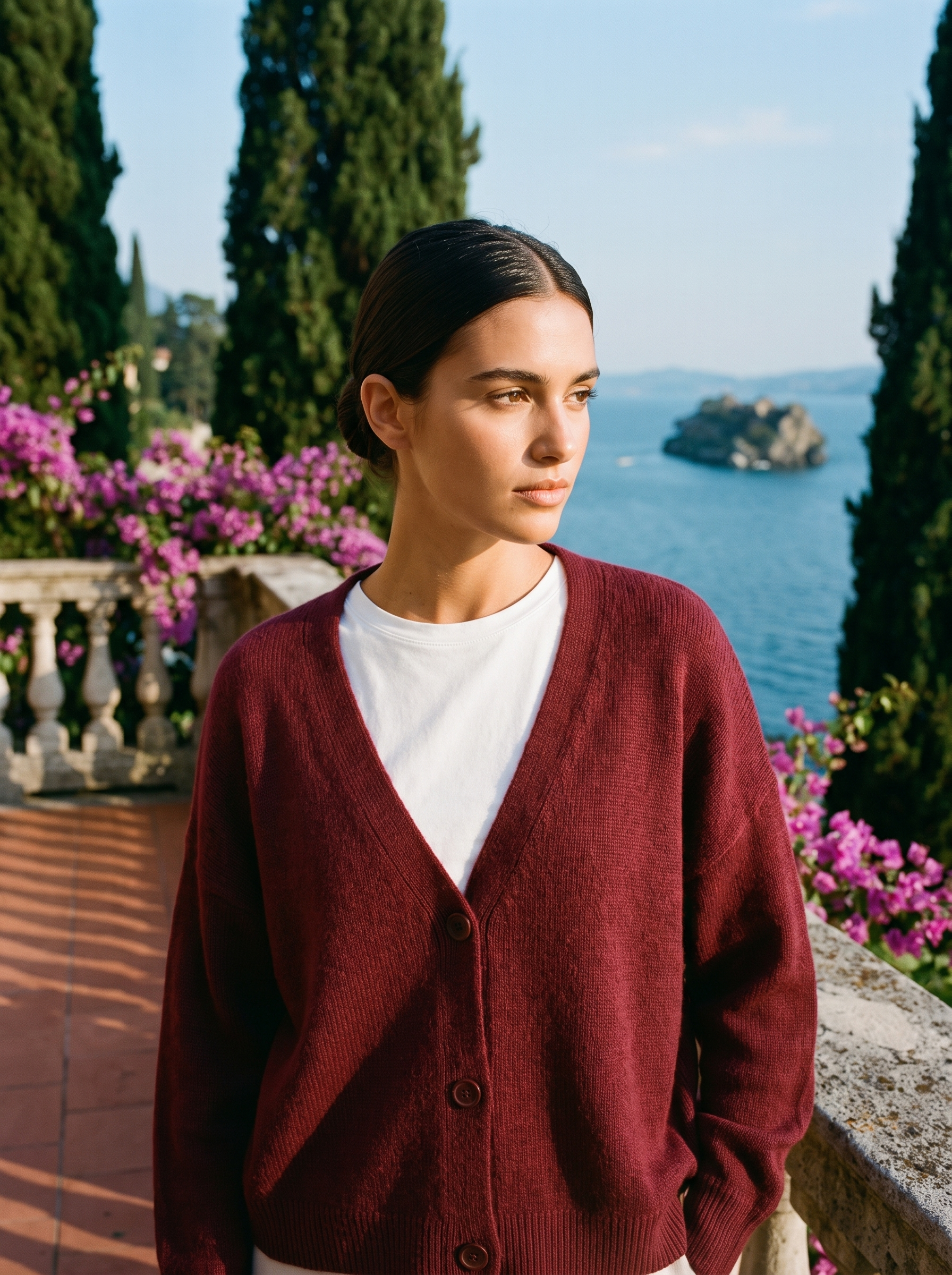 Woman wearing a burgundy V-neck cardigan on a terrace overlooking Lake Como, old money style — Aveloire