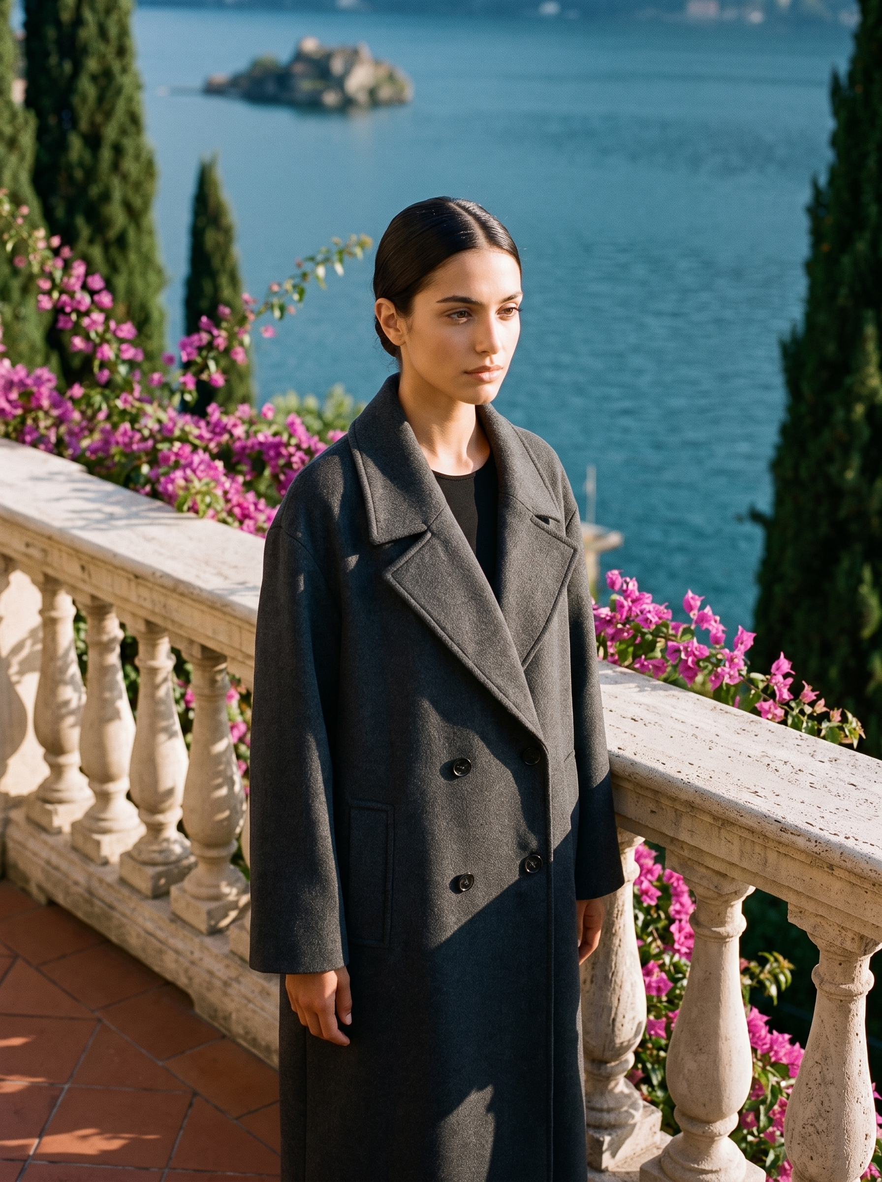 Woman wearing a charcoal-grey double-breasted wool overcoat on a Lake Como terrace — Aveloire