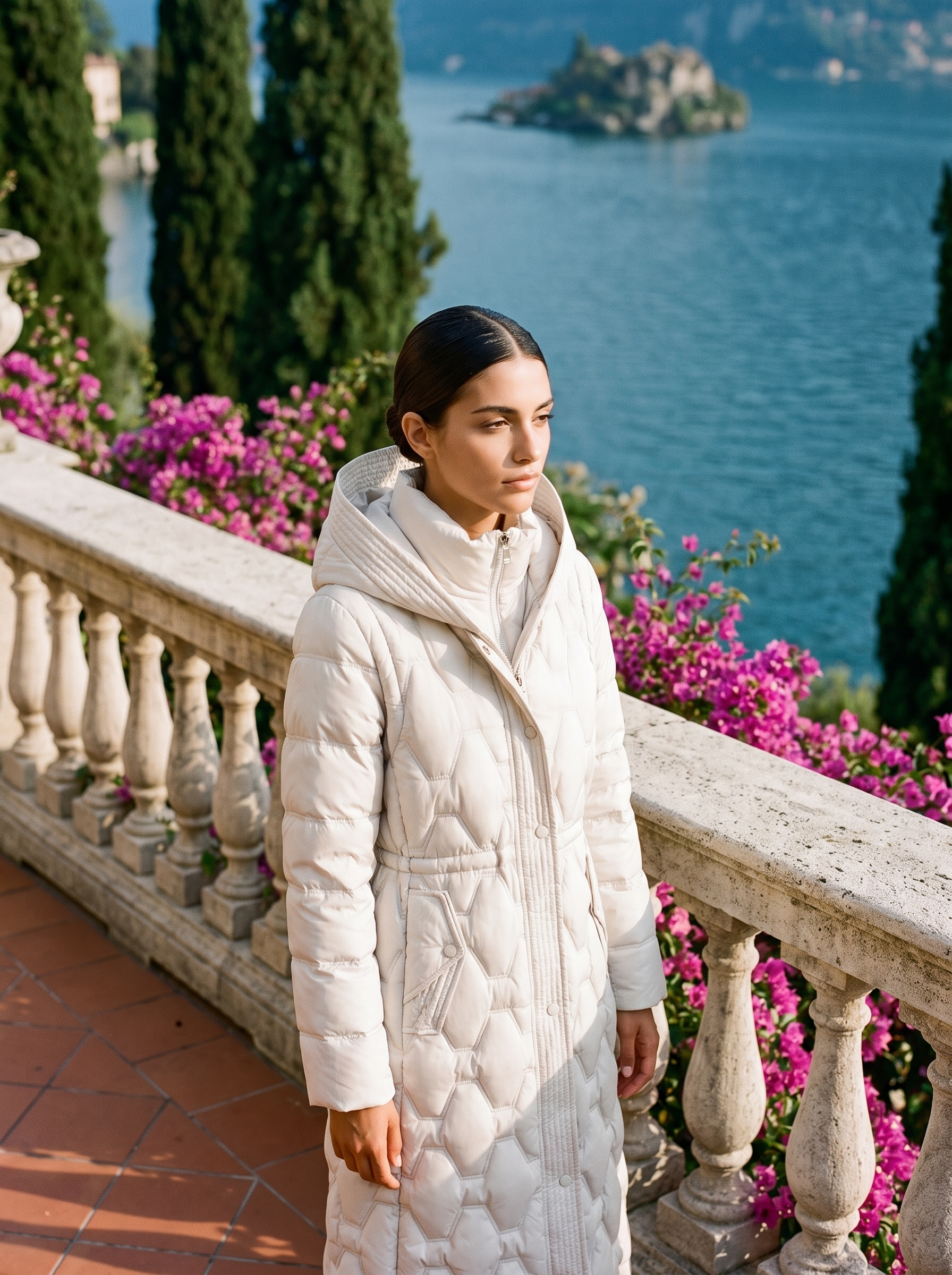 Woman wearing cream onion-quilted longline hooded puffer coat on a Lake Como terrace