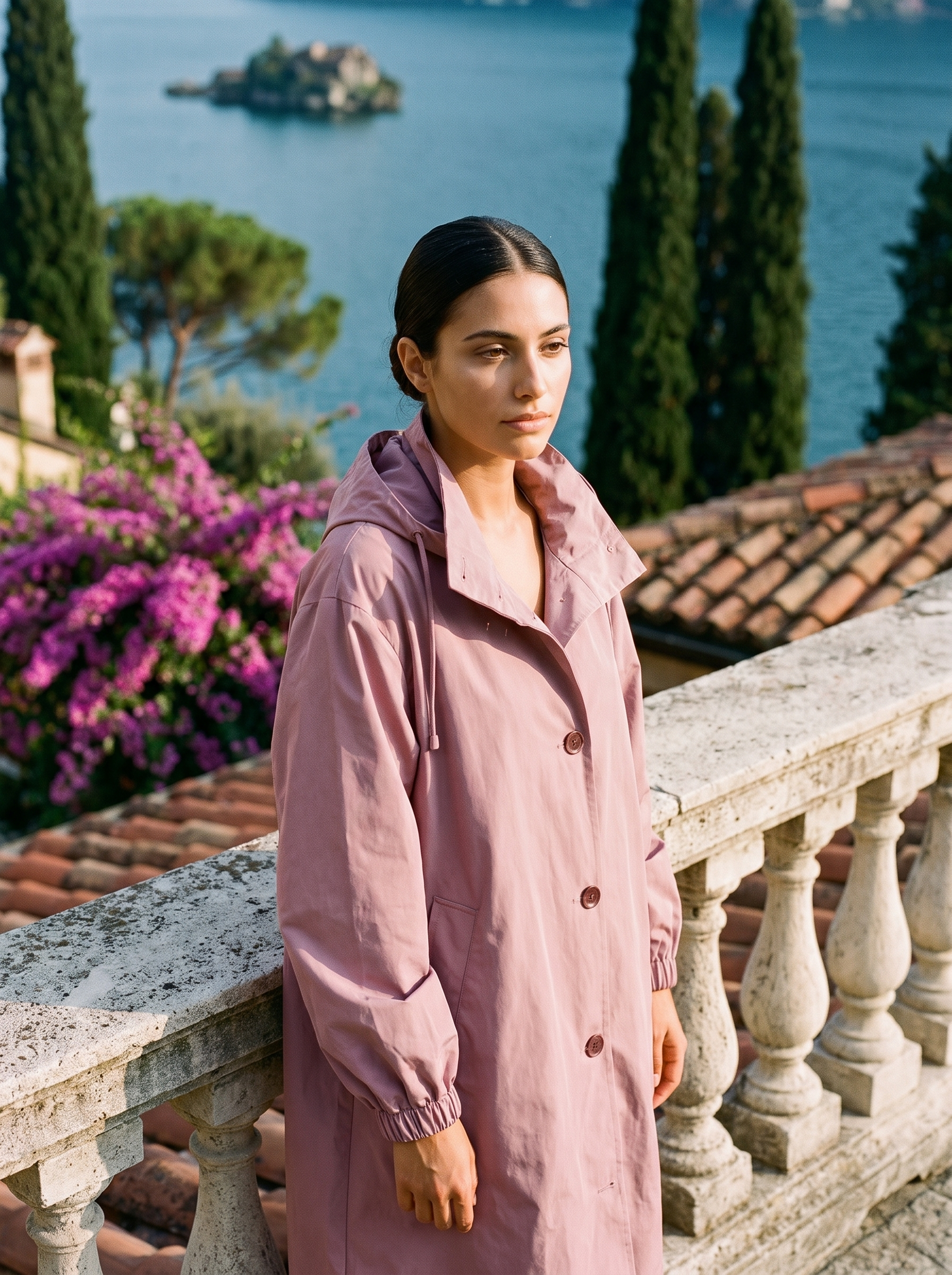 Woman wearing dusty pink water-repellent hooded raincoat on a Lake Como terrace
